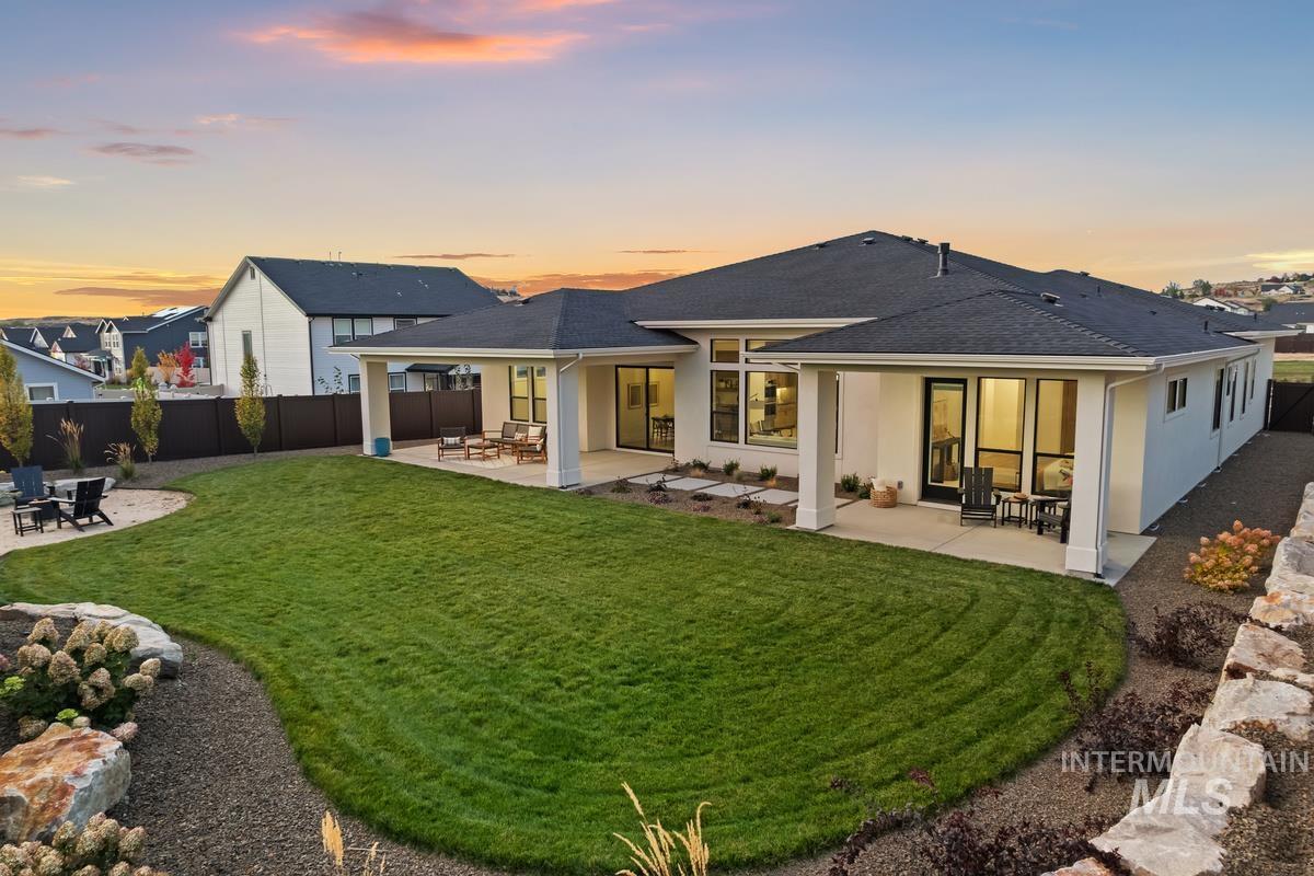 Back of house with a patio area, stucco siding, a fenced backyard, and a shingled roof