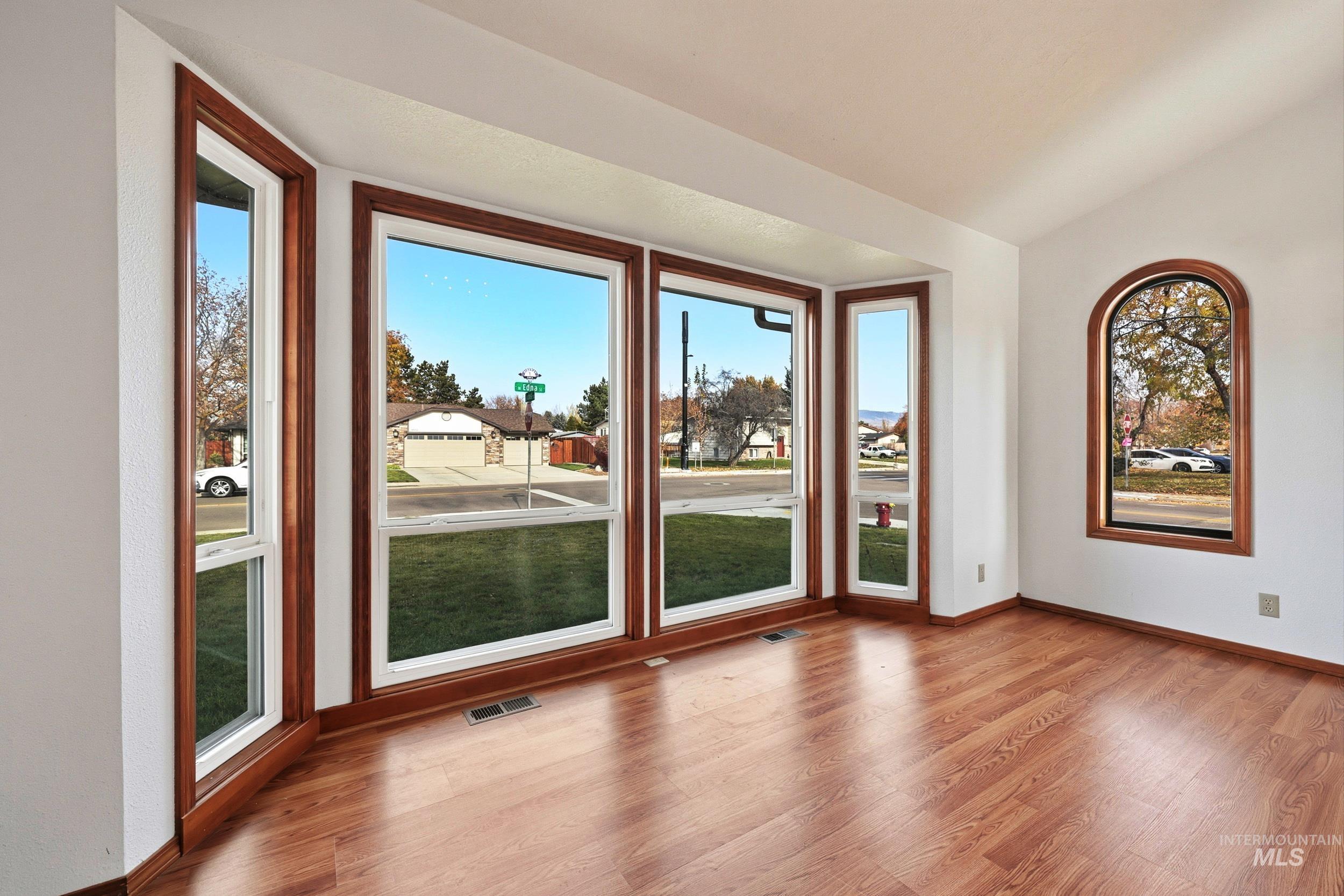 Unfurnished room featuring light wood-style flooring and vaulted ceiling