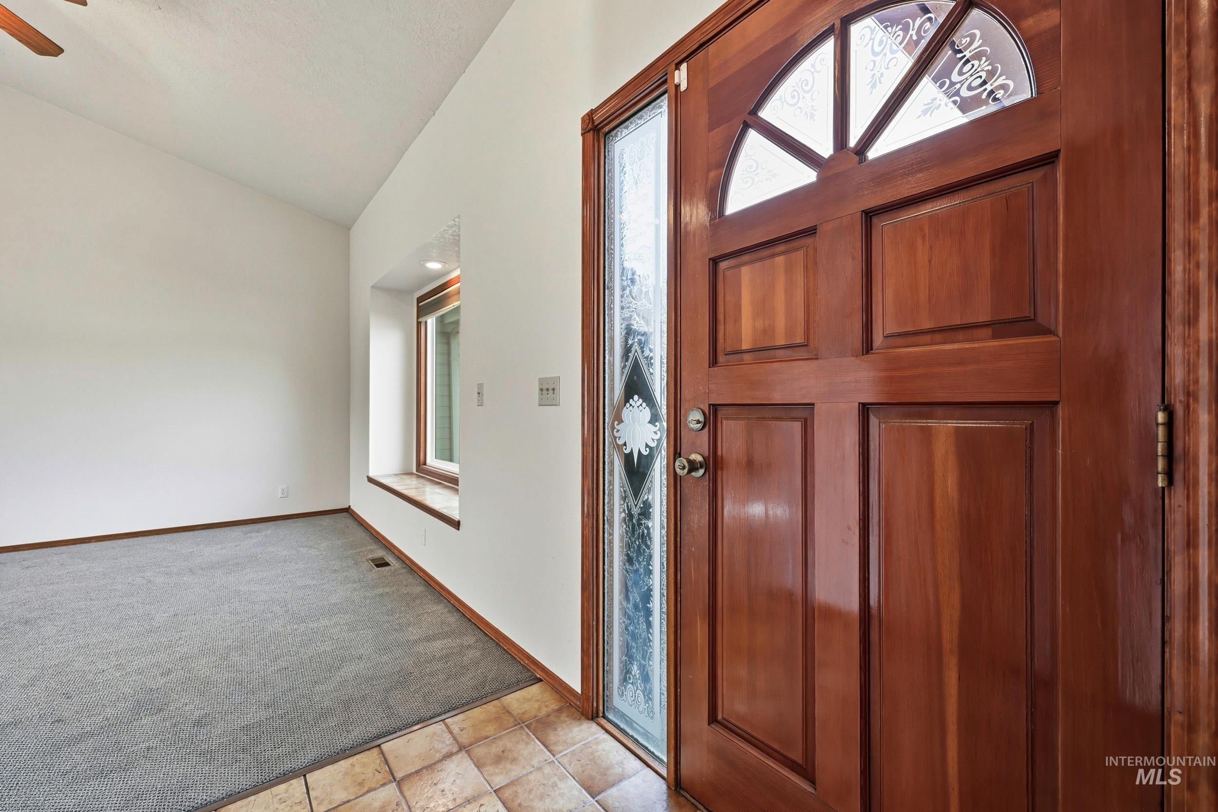 Foyer entrance featuring light carpet, lofted ceiling, and a ceiling fan