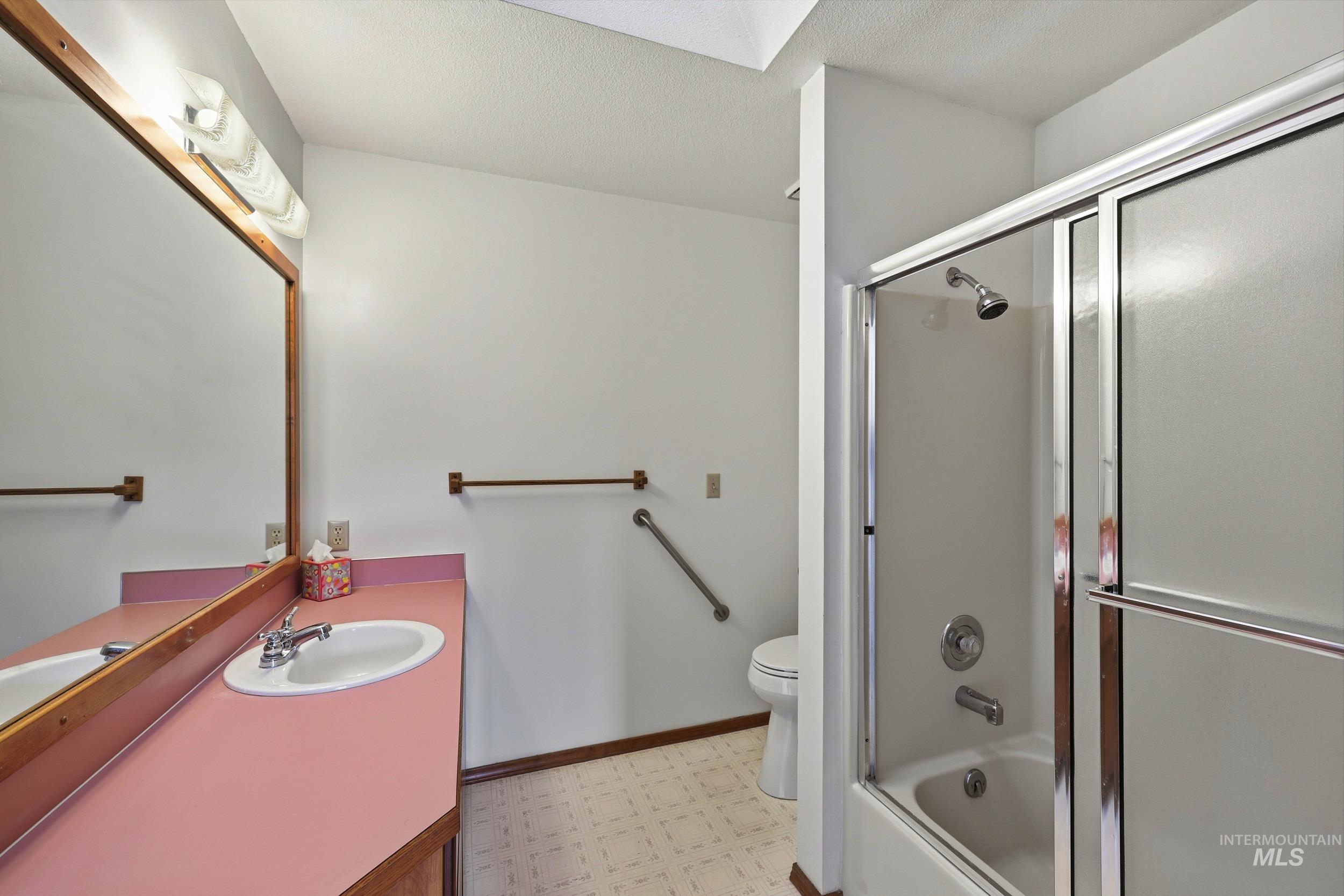 Full bathroom with light flooring, vanity, and enclosed tub / shower combo