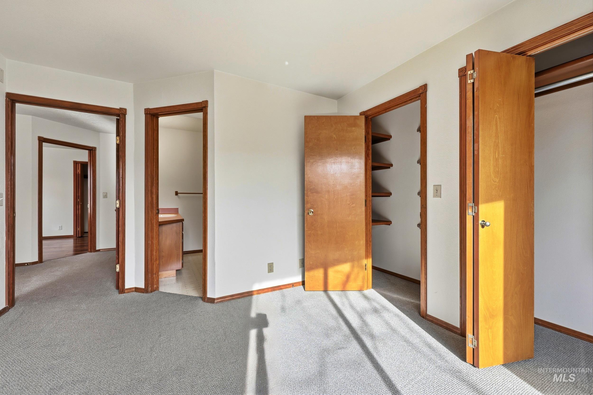 Unfurnished bedroom with a spacious closet, carpet, and connected bathroom