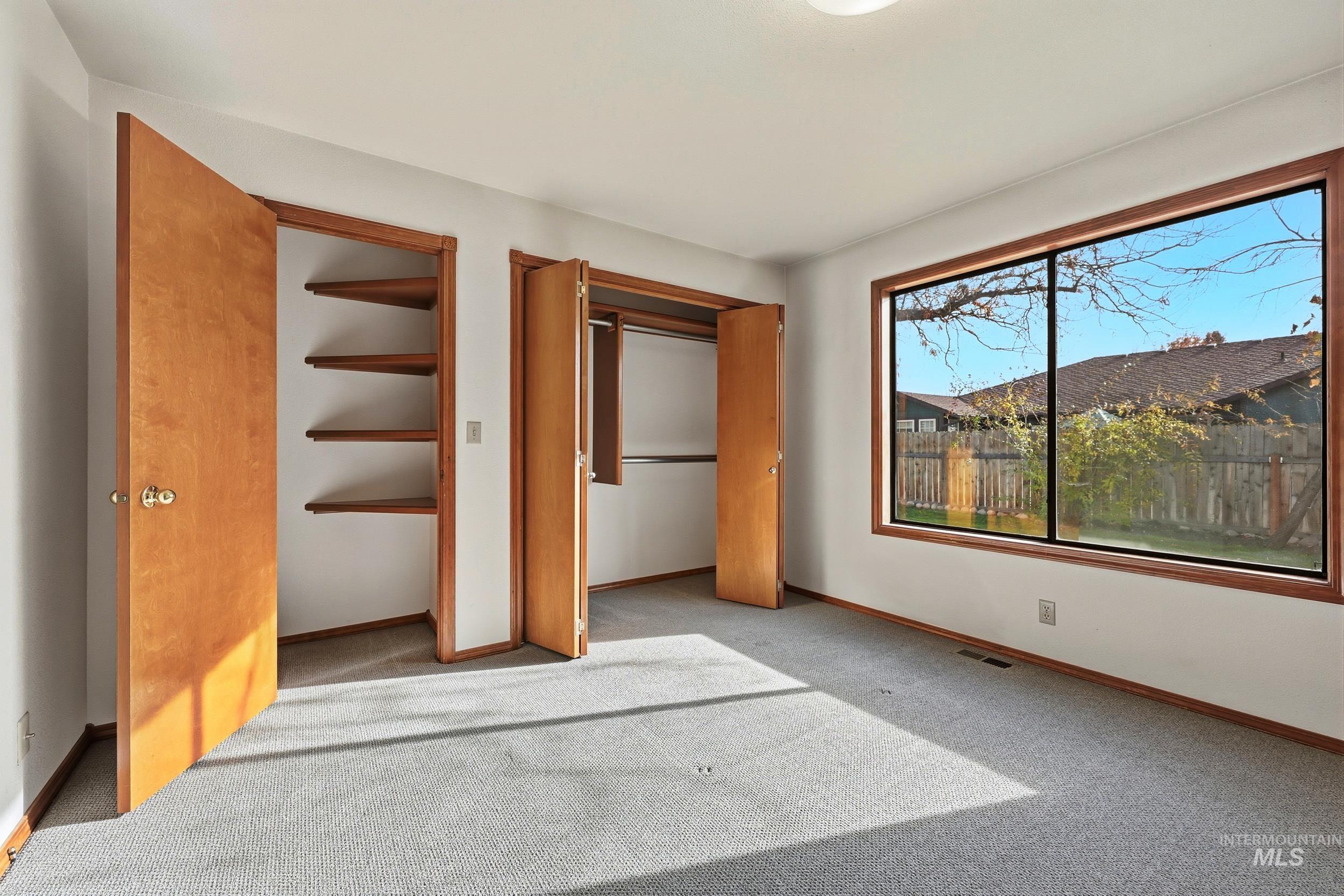 Unfurnished bedroom featuring carpet flooring and multiple closets