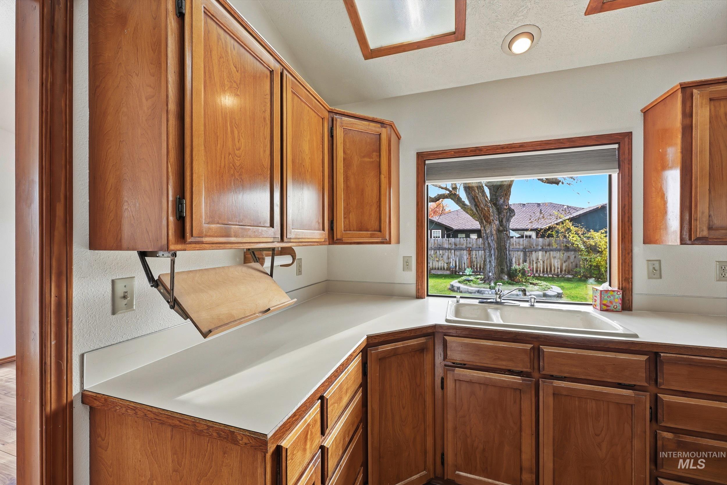 Kitchen with light countertops, brown cabinetry, and a textured ceiling
