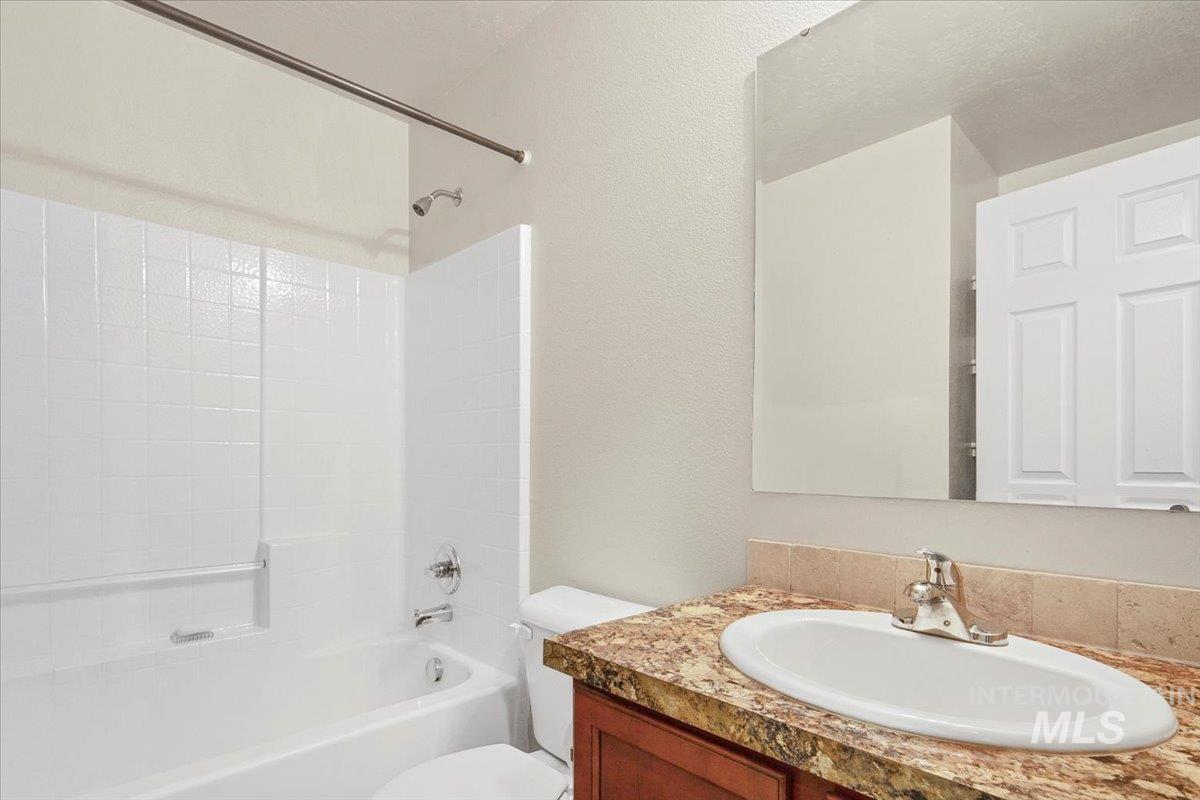 Bathroom featuring  shower combination, vanity, and a textured wall