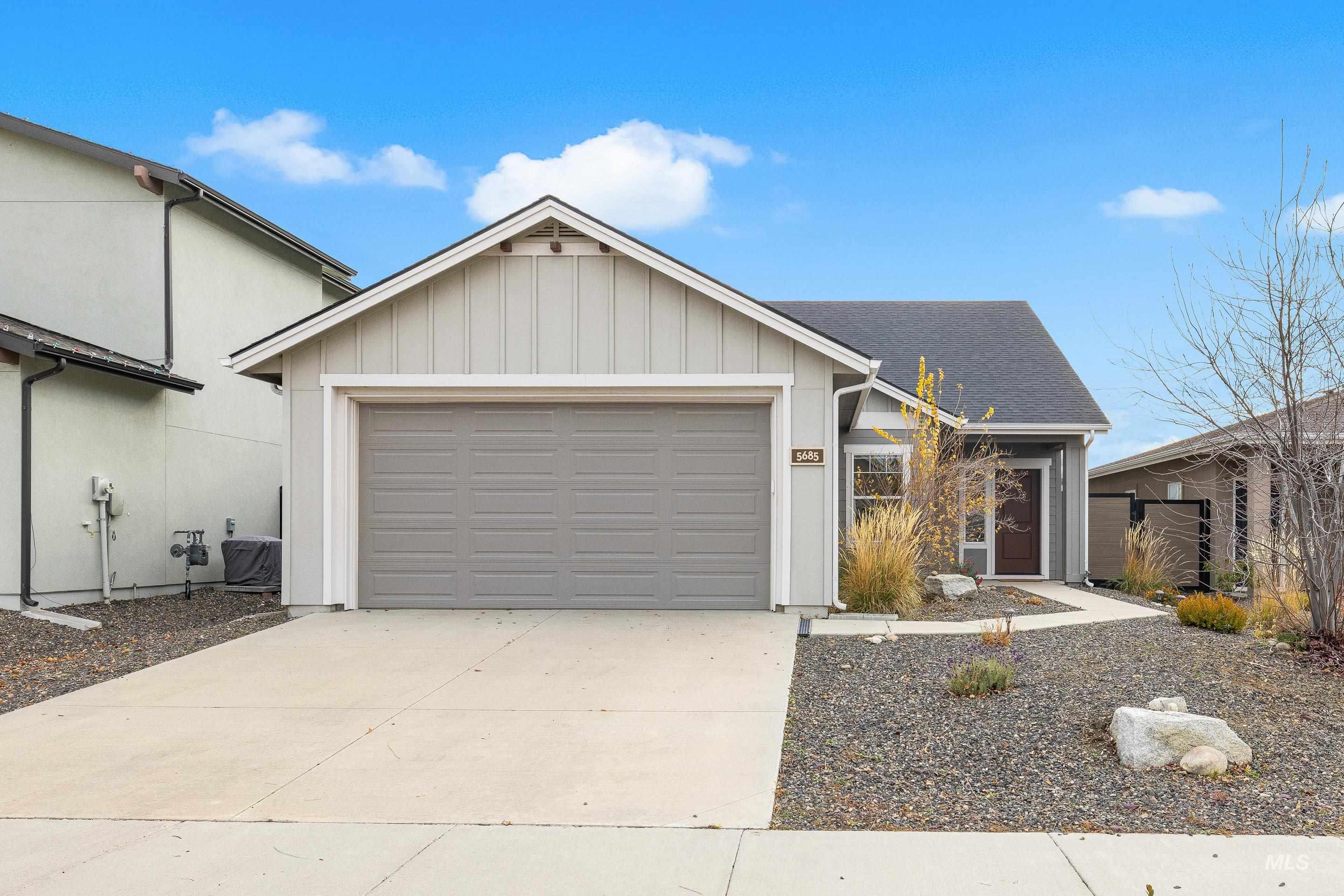 Single story home with board and batten siding, concrete driveway, an attached garage, and a shingled roof