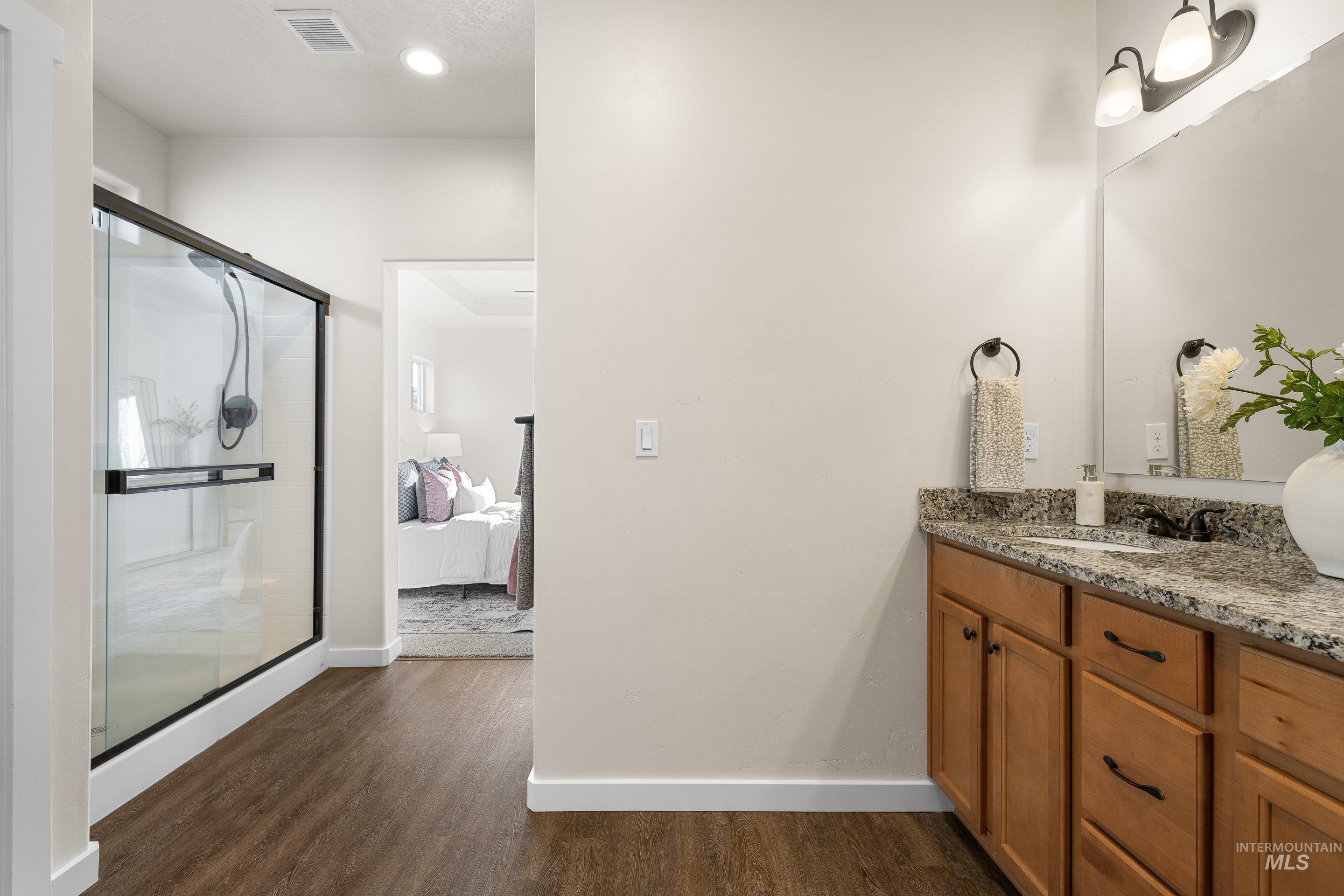 Ensuite bathroom featuring vanity, dark wood finished floors, and a stall shower