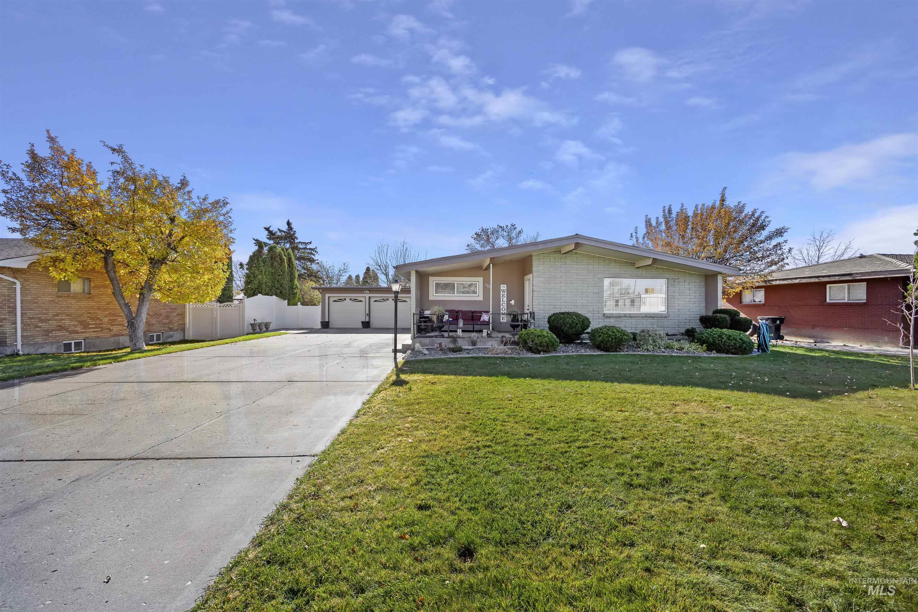 Mid-century inspired home with brick siding, a garage, and driveway