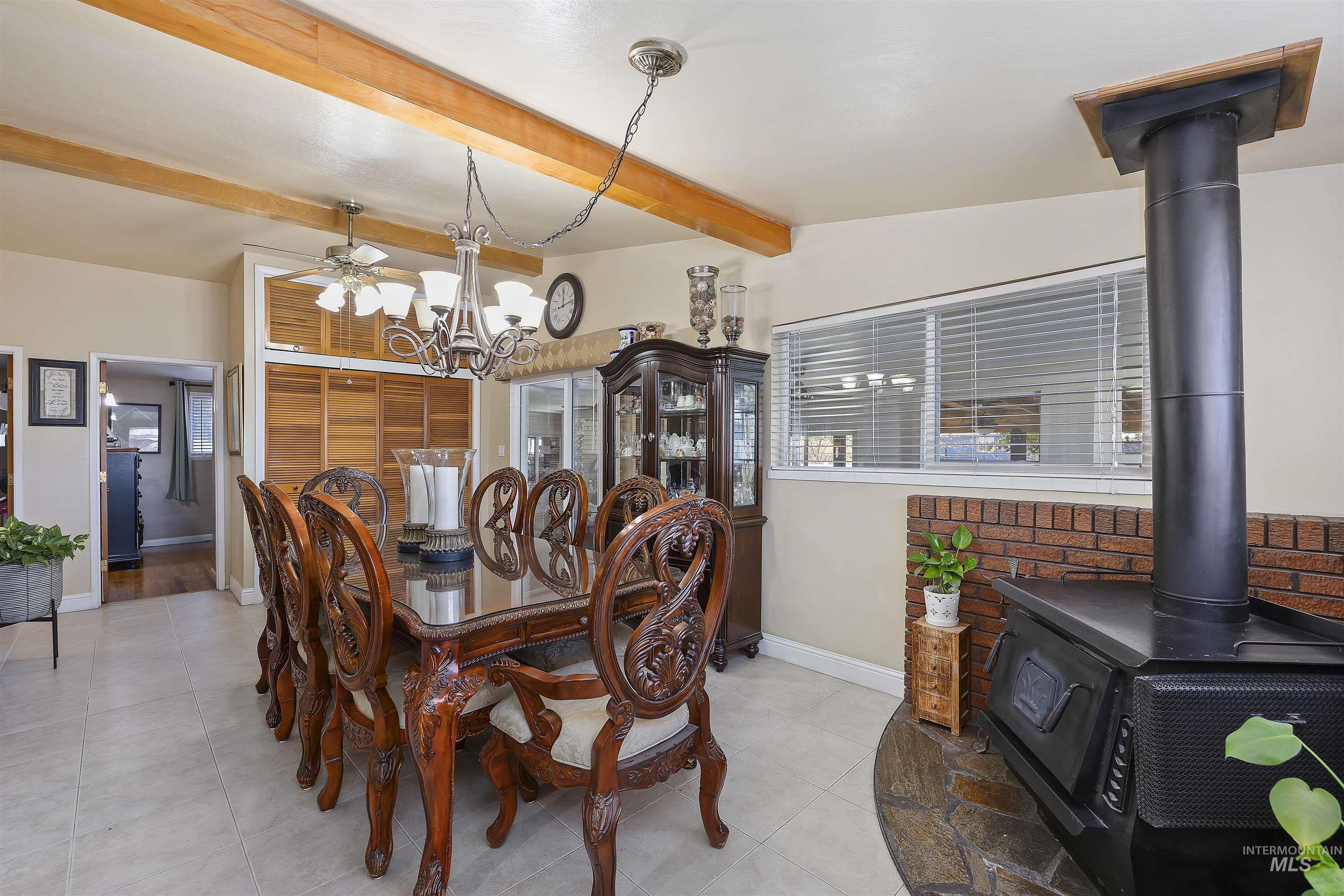 Dining area with a wood stove, light tile patterned flooring, and a chandelier