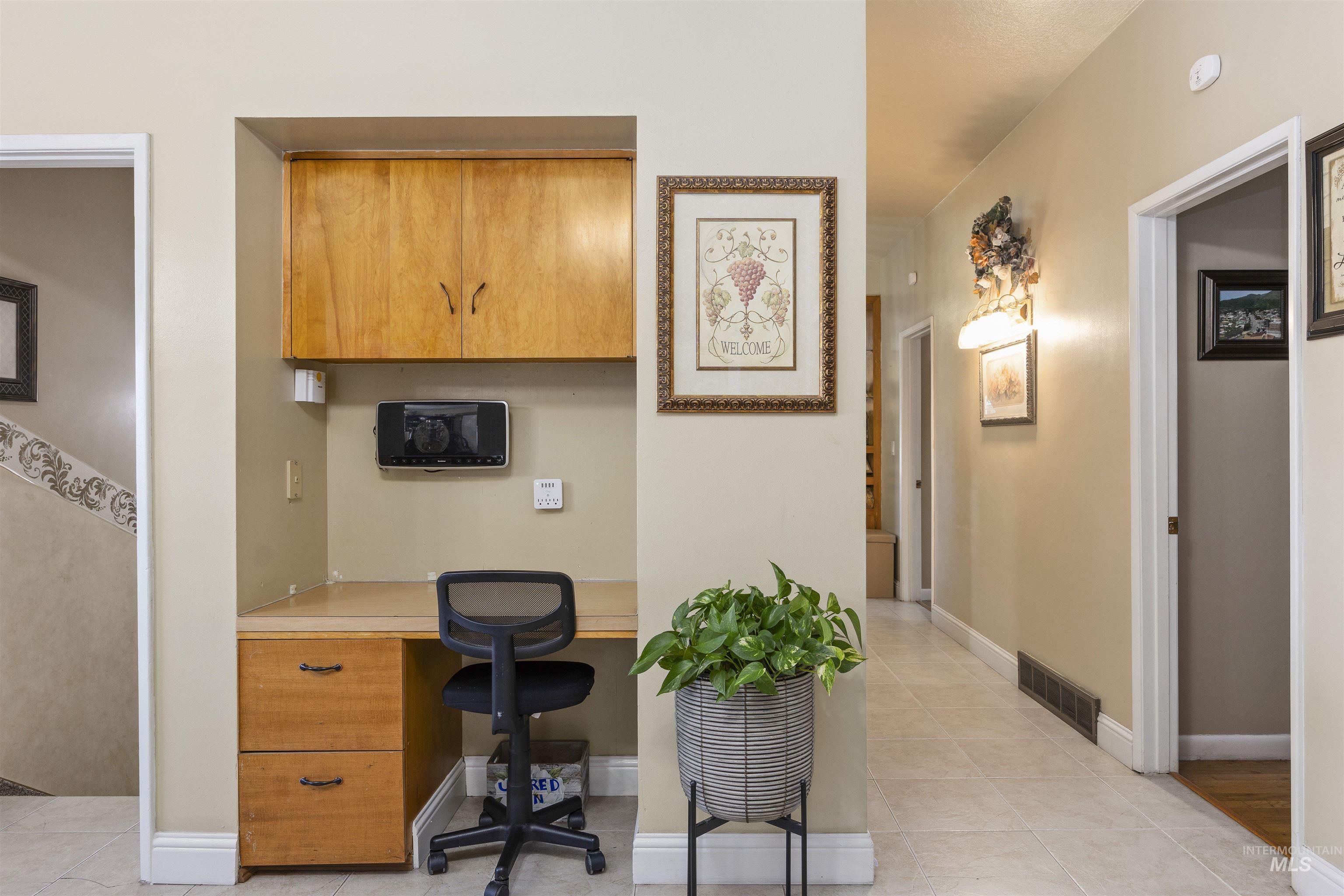Office area featuring light tile patterned floors and built in study area