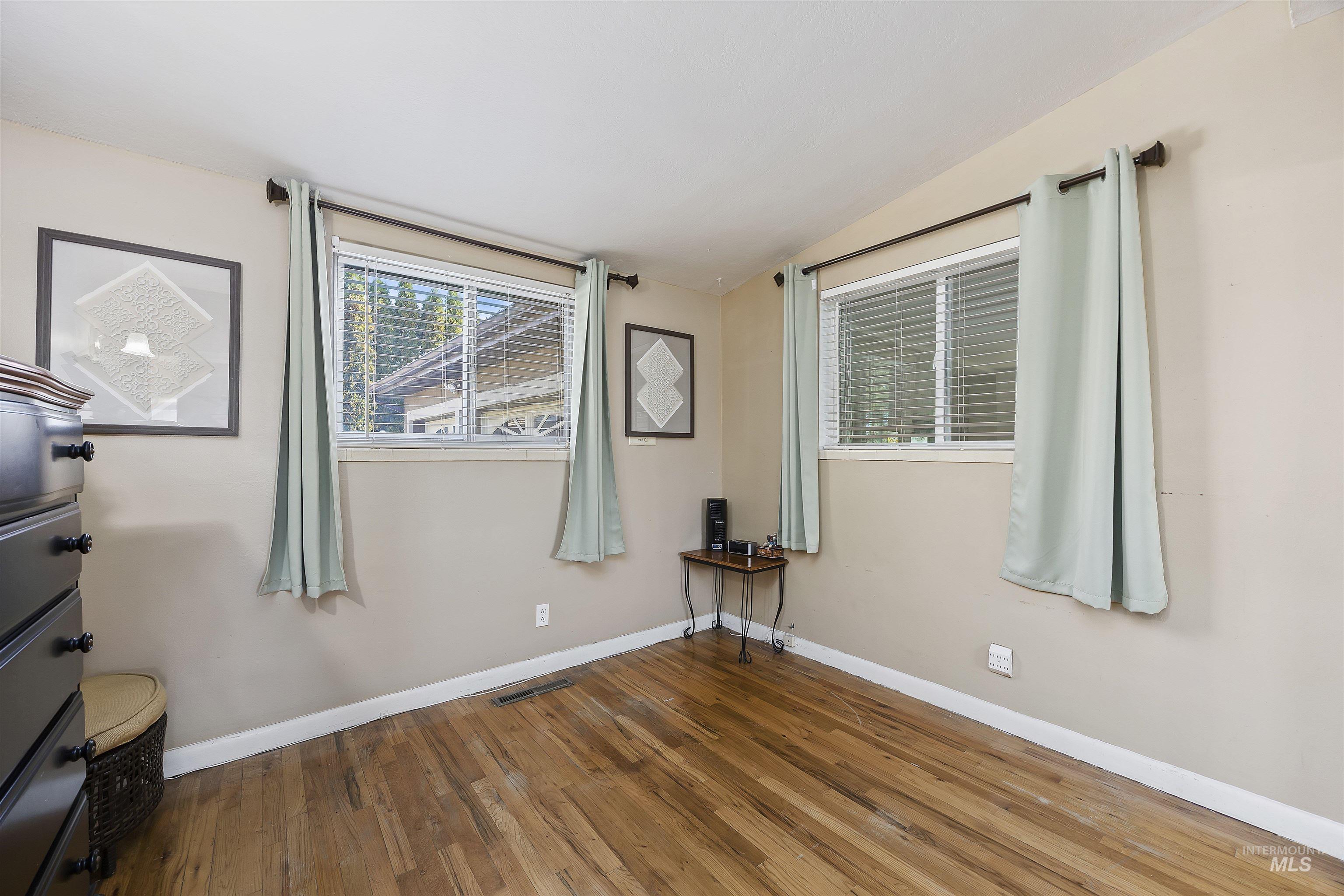 Unfurnished bedroom with wood finished floors and vaulted ceiling