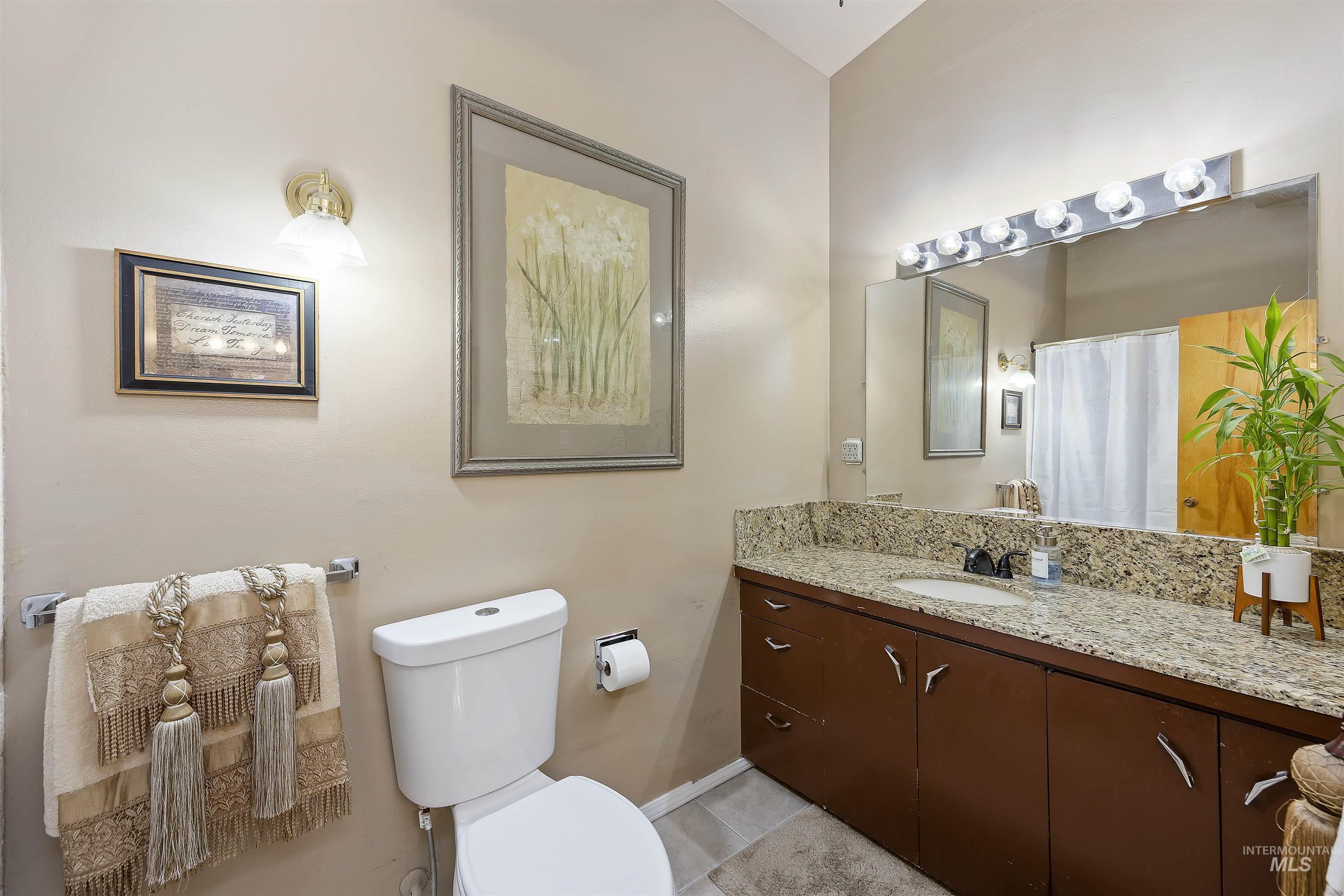 Full bath featuring vanity, a shower with shower curtain, and light tile patterned flooring