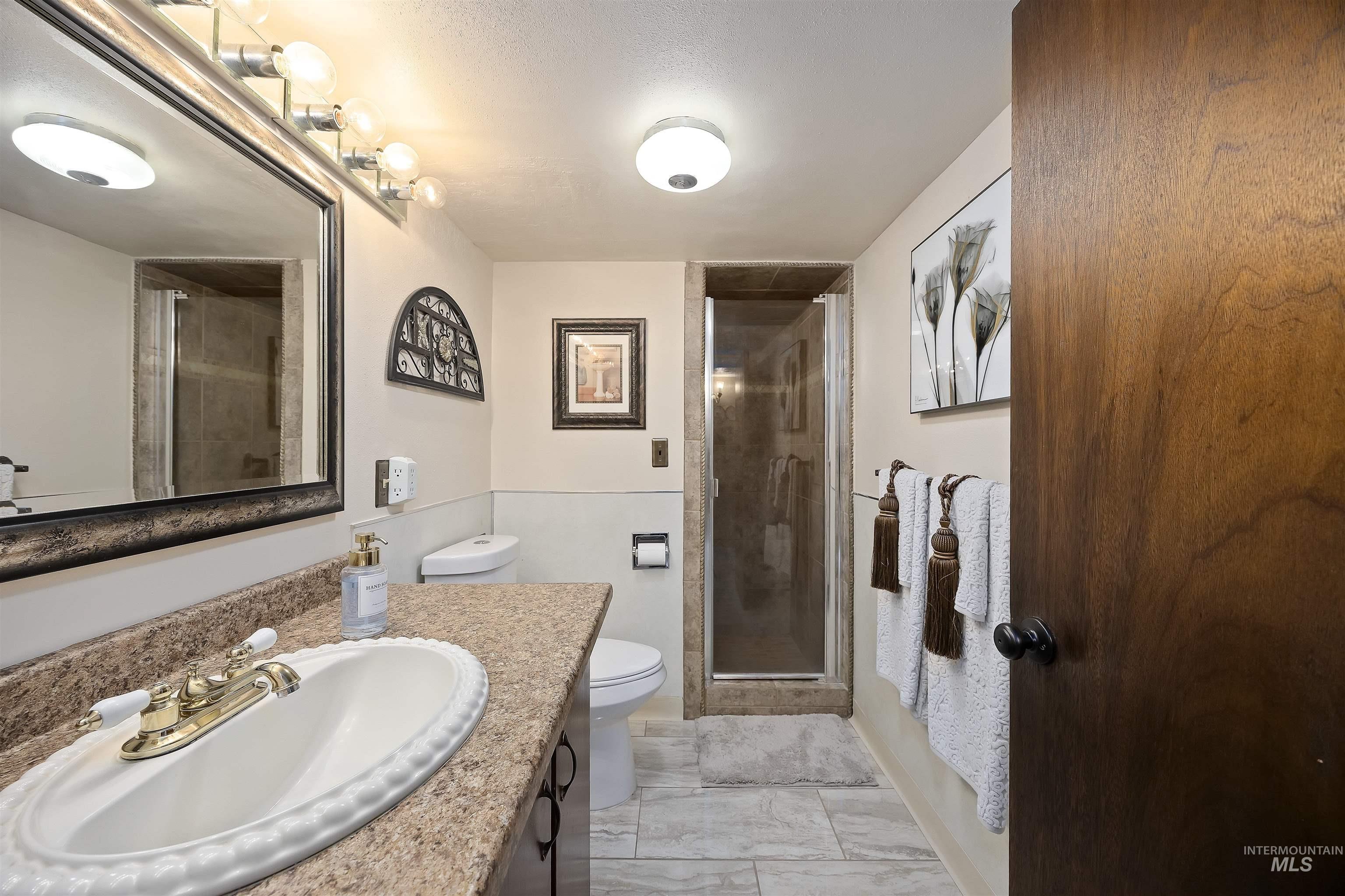 Bathroom featuring a stall shower, vanity, and light marble finish flooring