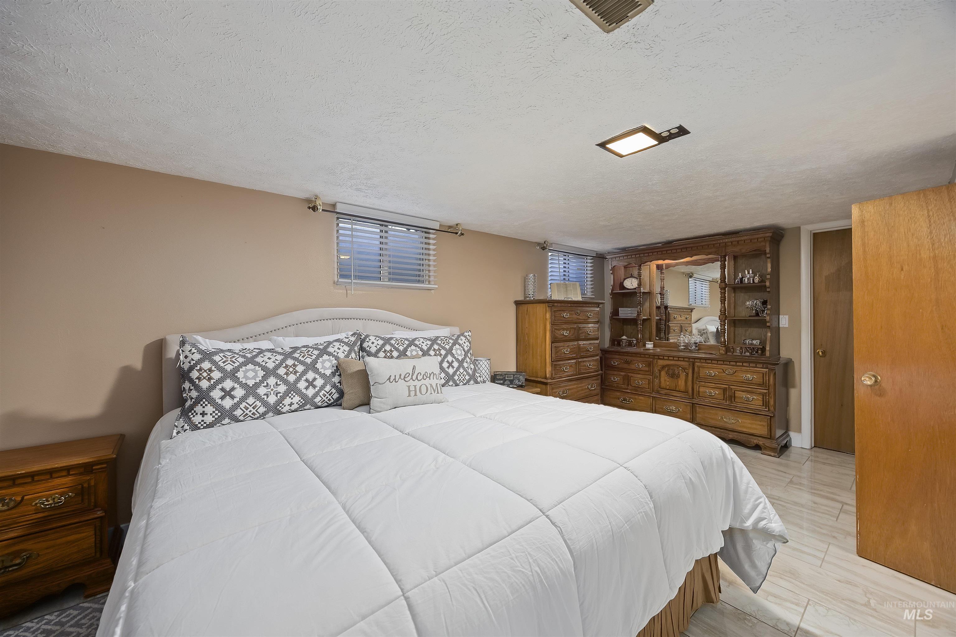 Bedroom with a textured ceiling and light wood-type flooring