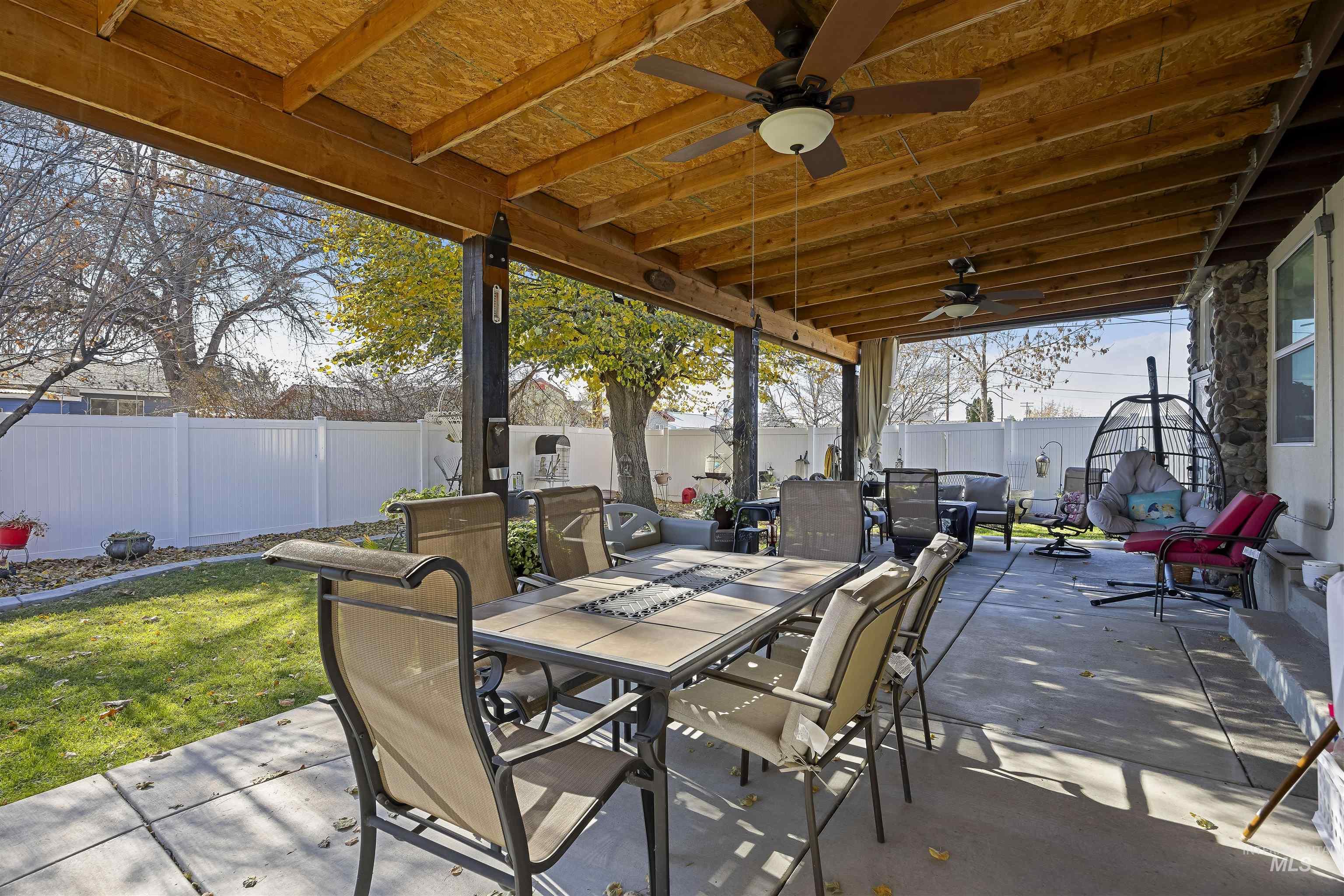 Fenced backyard with a patio, outdoor dining space, and a ceiling fan