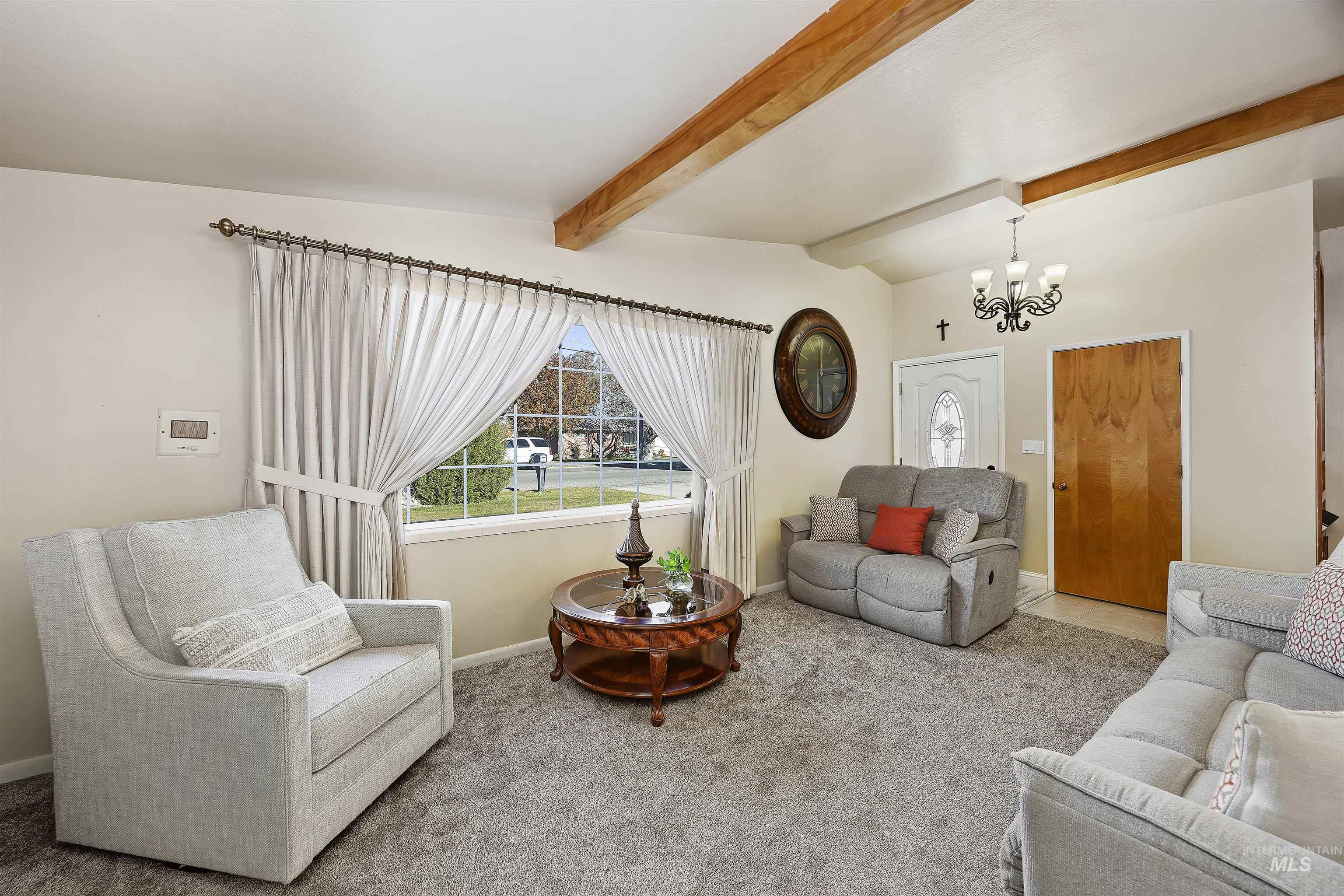Carpeted living area with a chandelier and baseboards