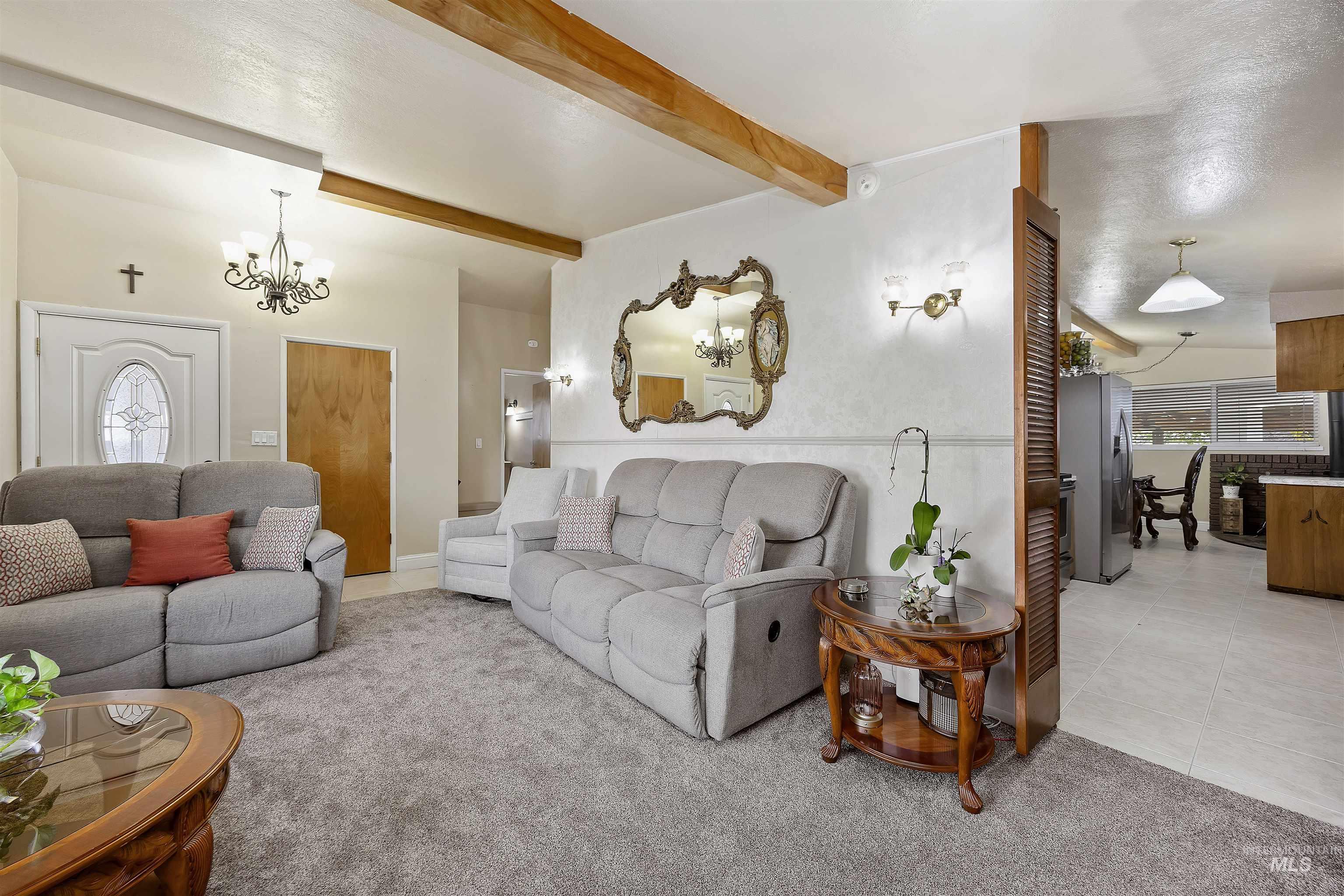 Living area featuring plenty of natural light, beam ceiling, a chandelier, light carpet, and light tile patterned floors