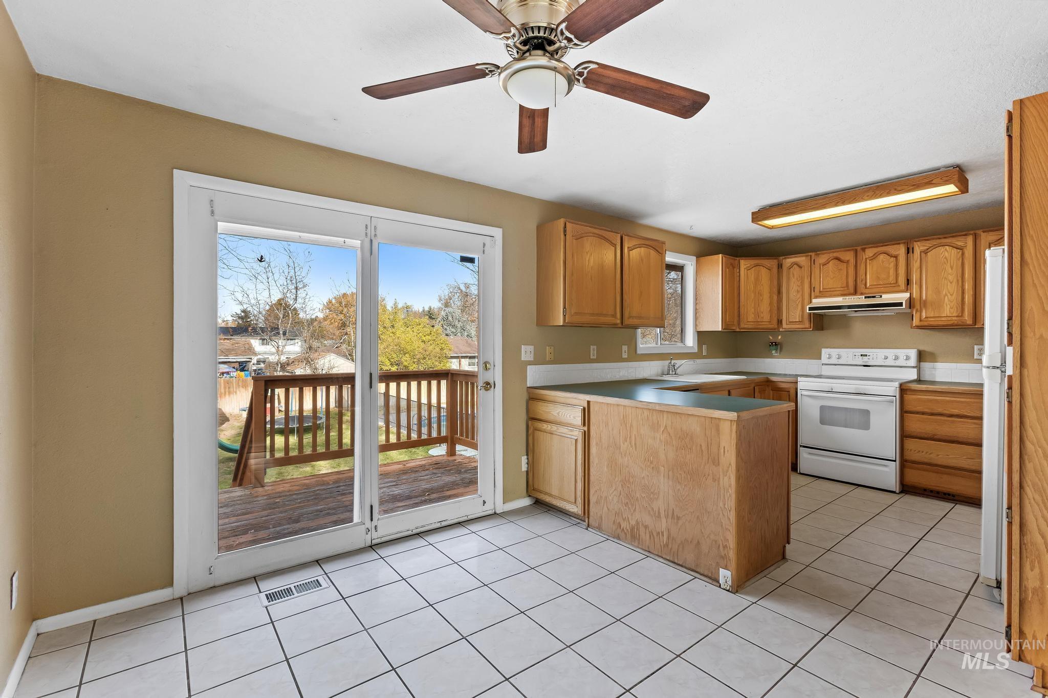 Kitchen with electric range, light tile patterned floors, a peninsula, and light countertops