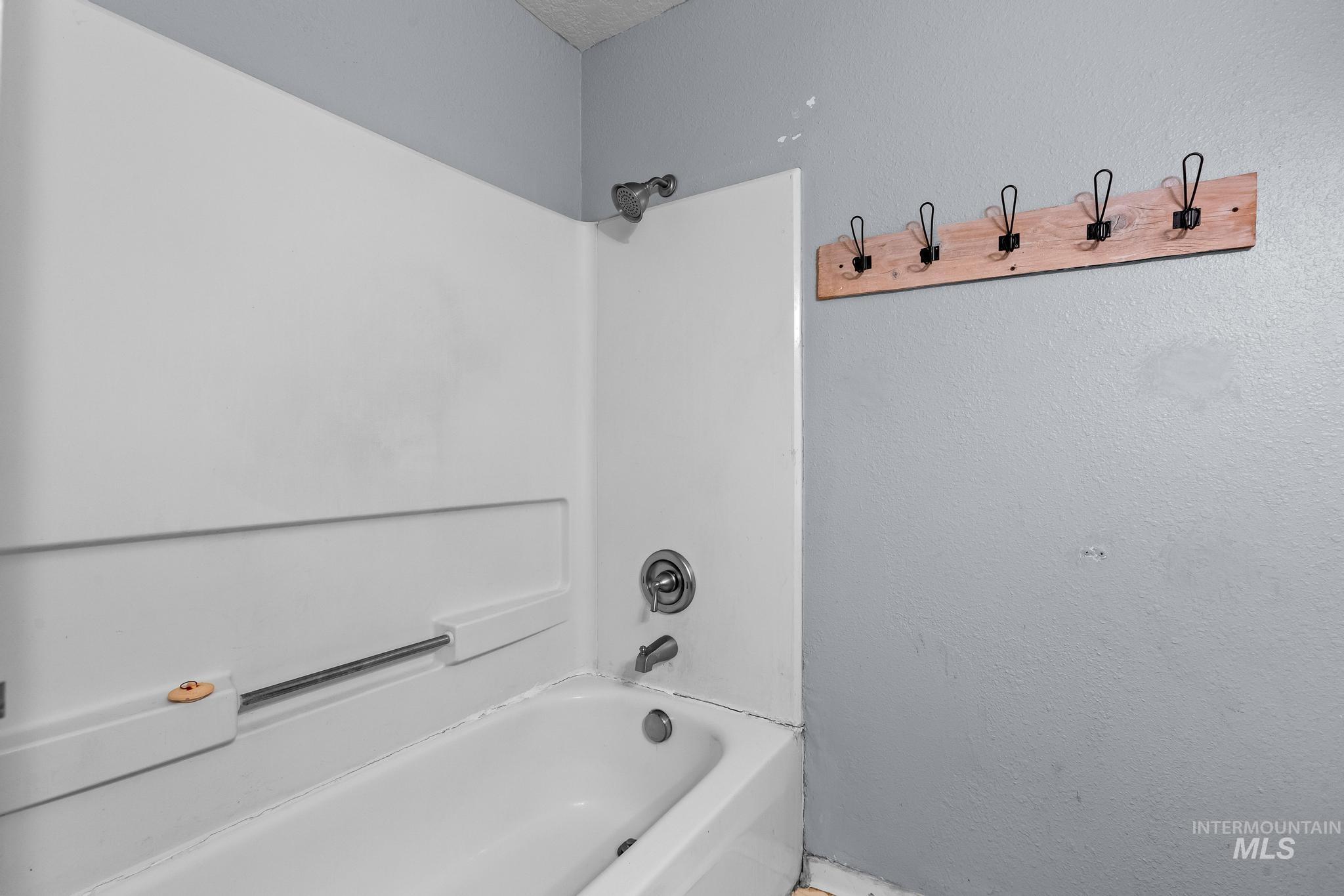 Full bath featuring shower / tub combination and a textured wall