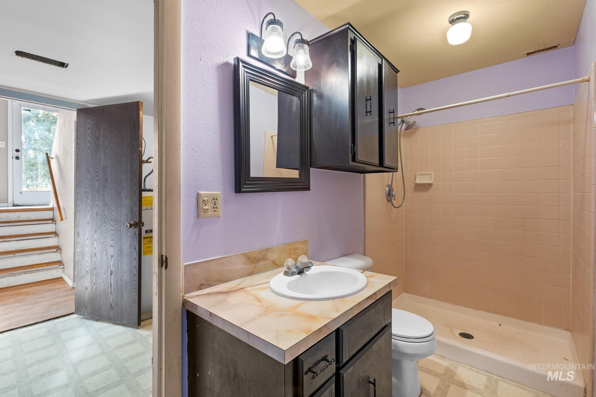 Full bathroom featuring light floors, vanity, and a shower stall