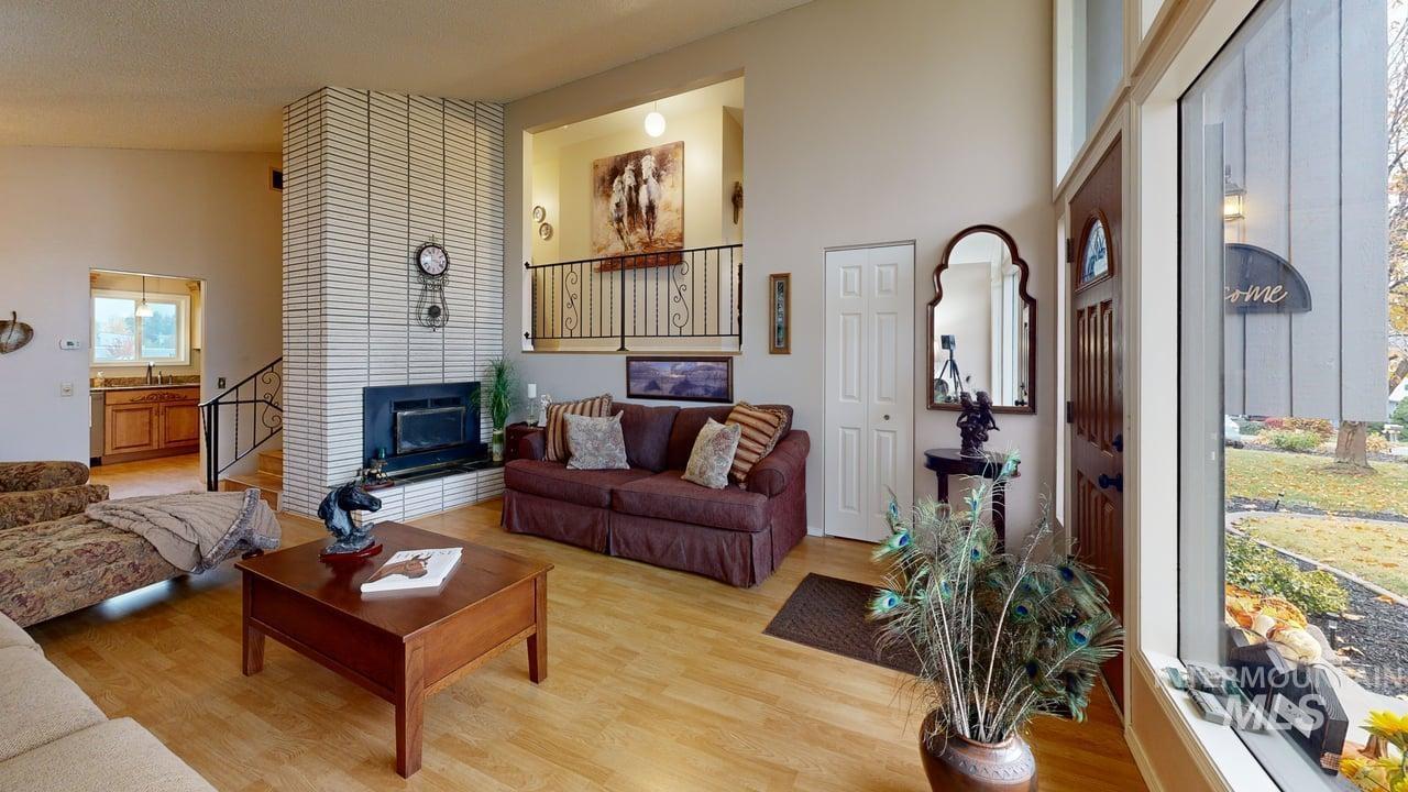 Living area with wood finished floors, a fireplace, a high ceiling, and stairs