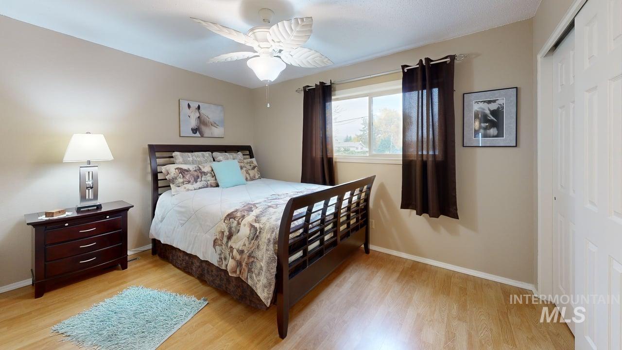 Bedroom with a closet, light wood finished floors, and a ceiling fan