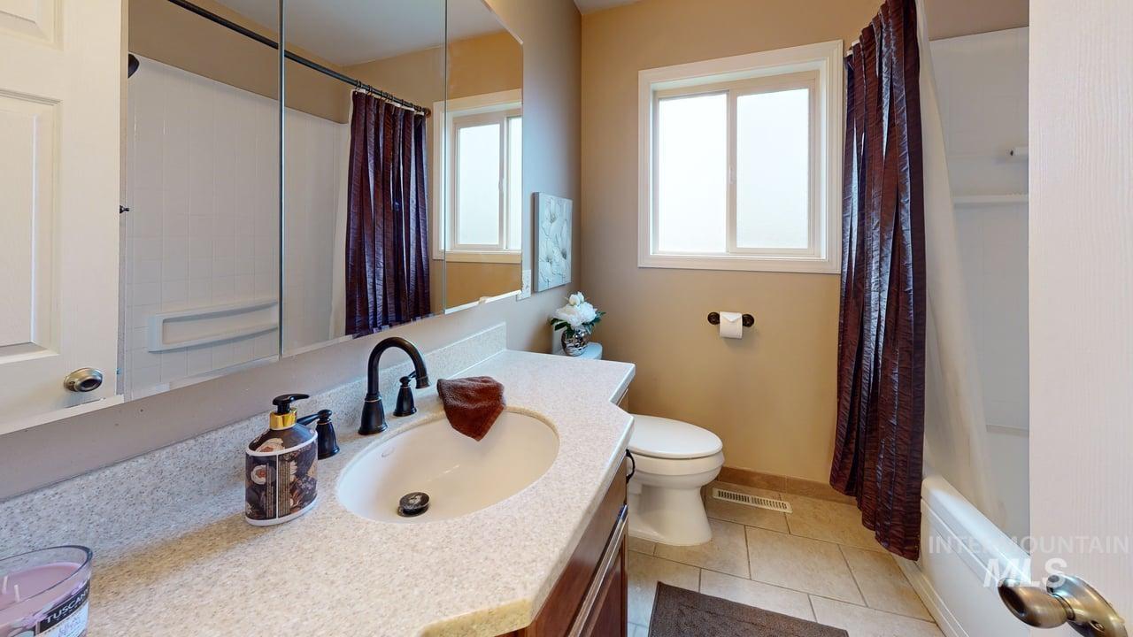 Bathroom with light tile patterned floors, vanity, and shower / bath combo