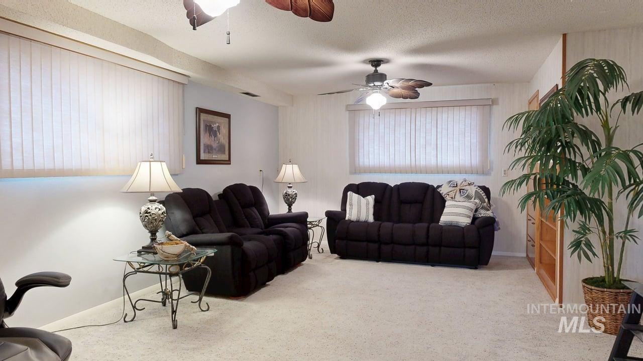 Living area with carpet, a textured ceiling, and a ceiling fan