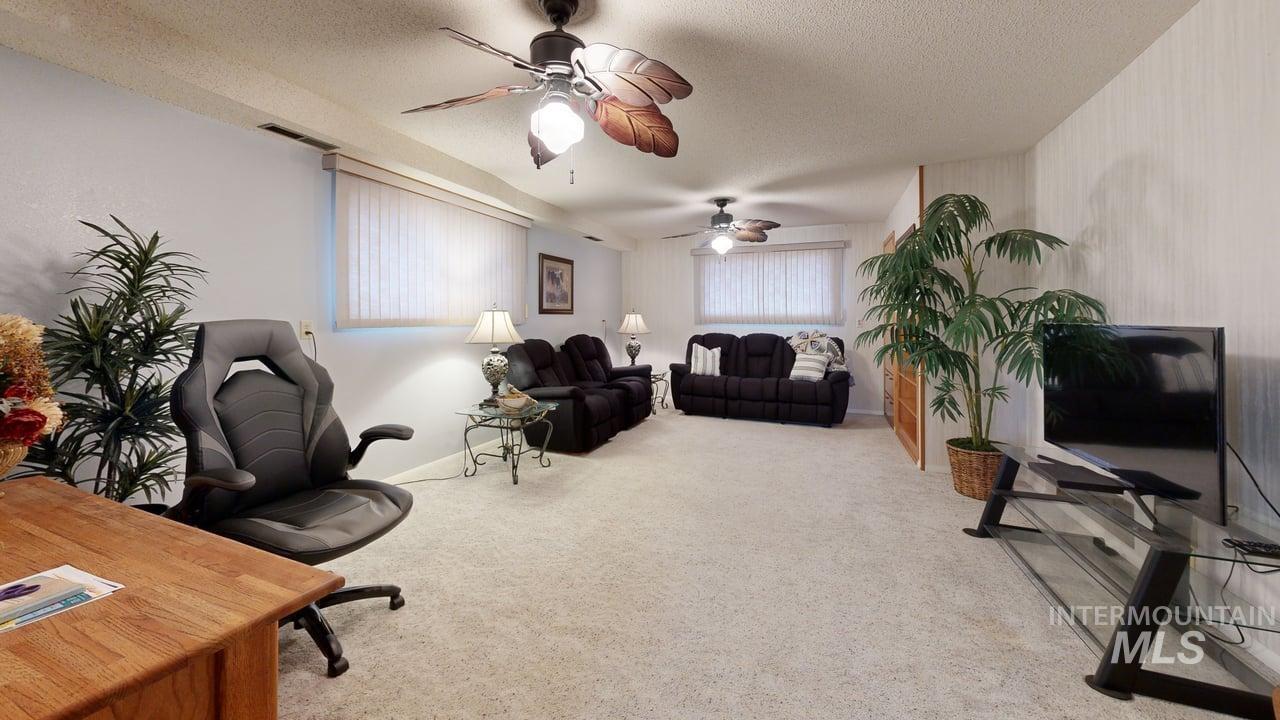 Office area with light carpet, a textured ceiling, and a ceiling fan