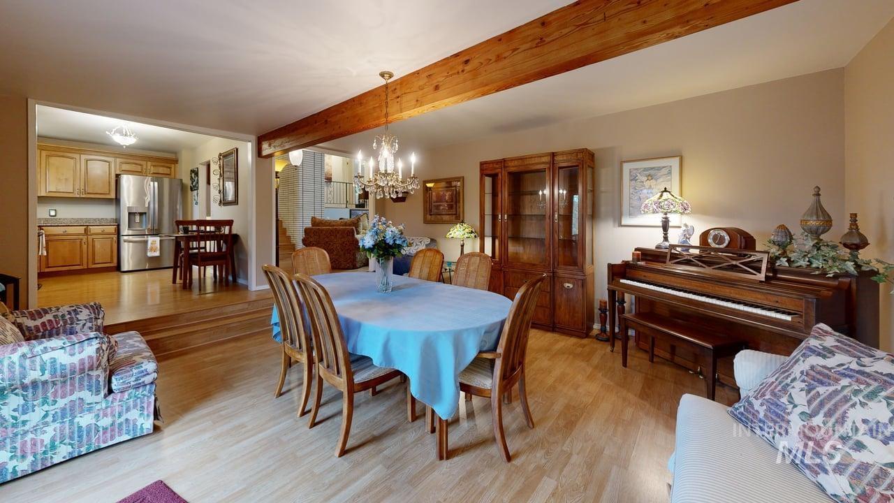 Dining room featuring beamed ceiling, light wood-style flooring, and a chandelier
