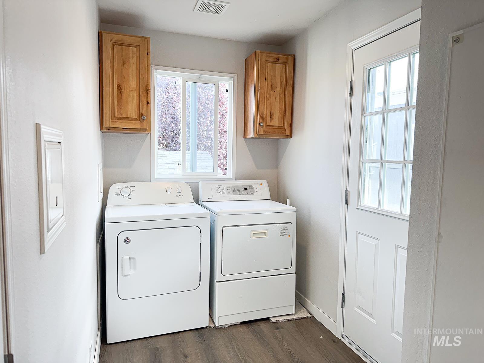 Laundry area featuring cabinet space, plenty of natural light, dark wood-style flooring, and independent washer and dryer