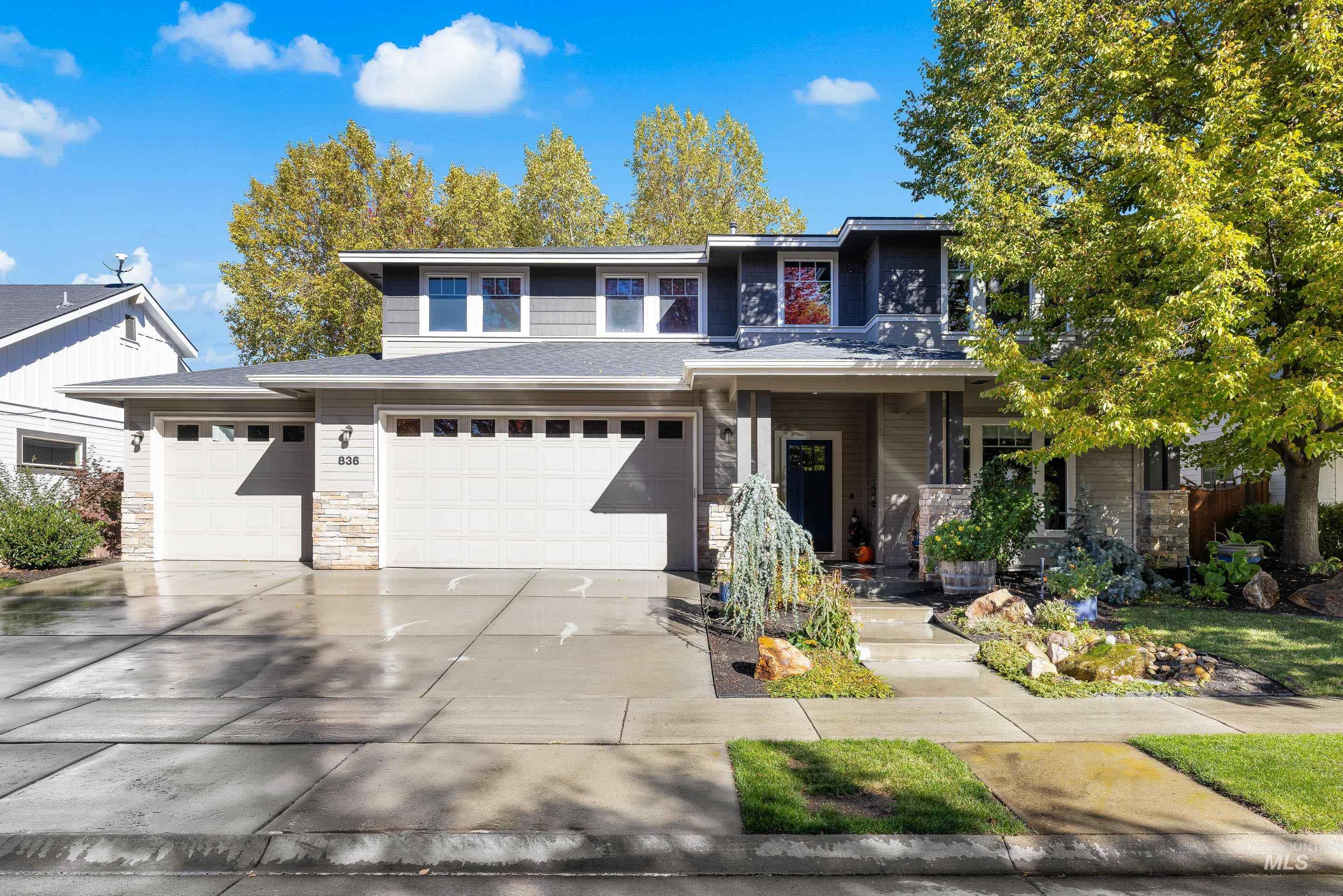 Prairie-style home featuring stone siding, concrete driveway, and covered porch
