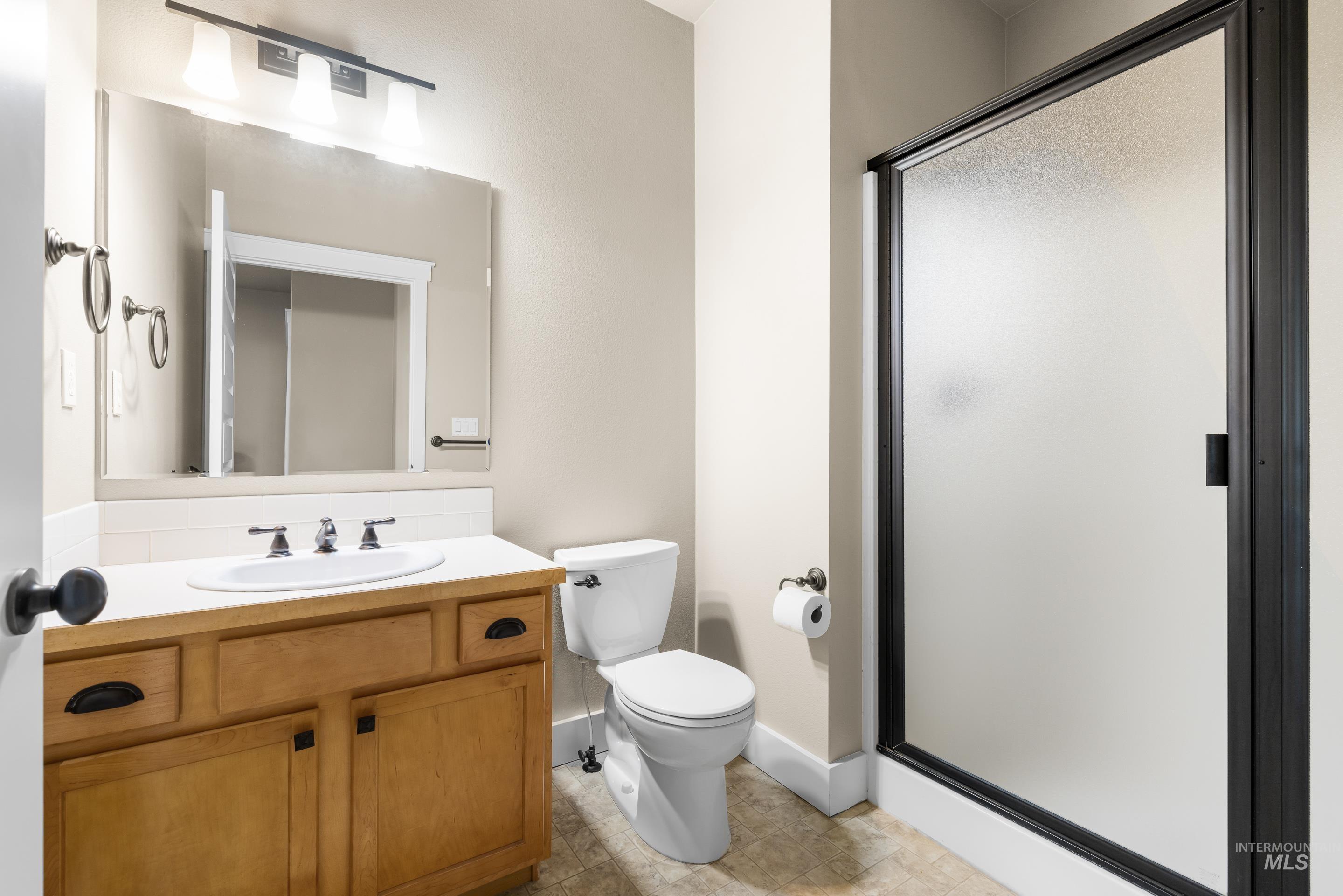 Full bath featuring a shower stall, vanity, and light tile patterned floors