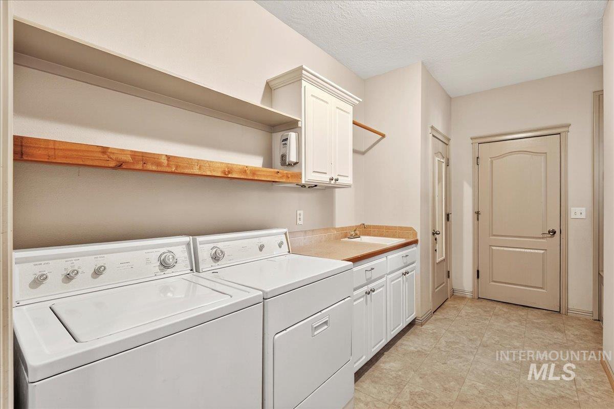 Laundry area featuring separate washer and dryer, a textured ceiling, and cabinet space