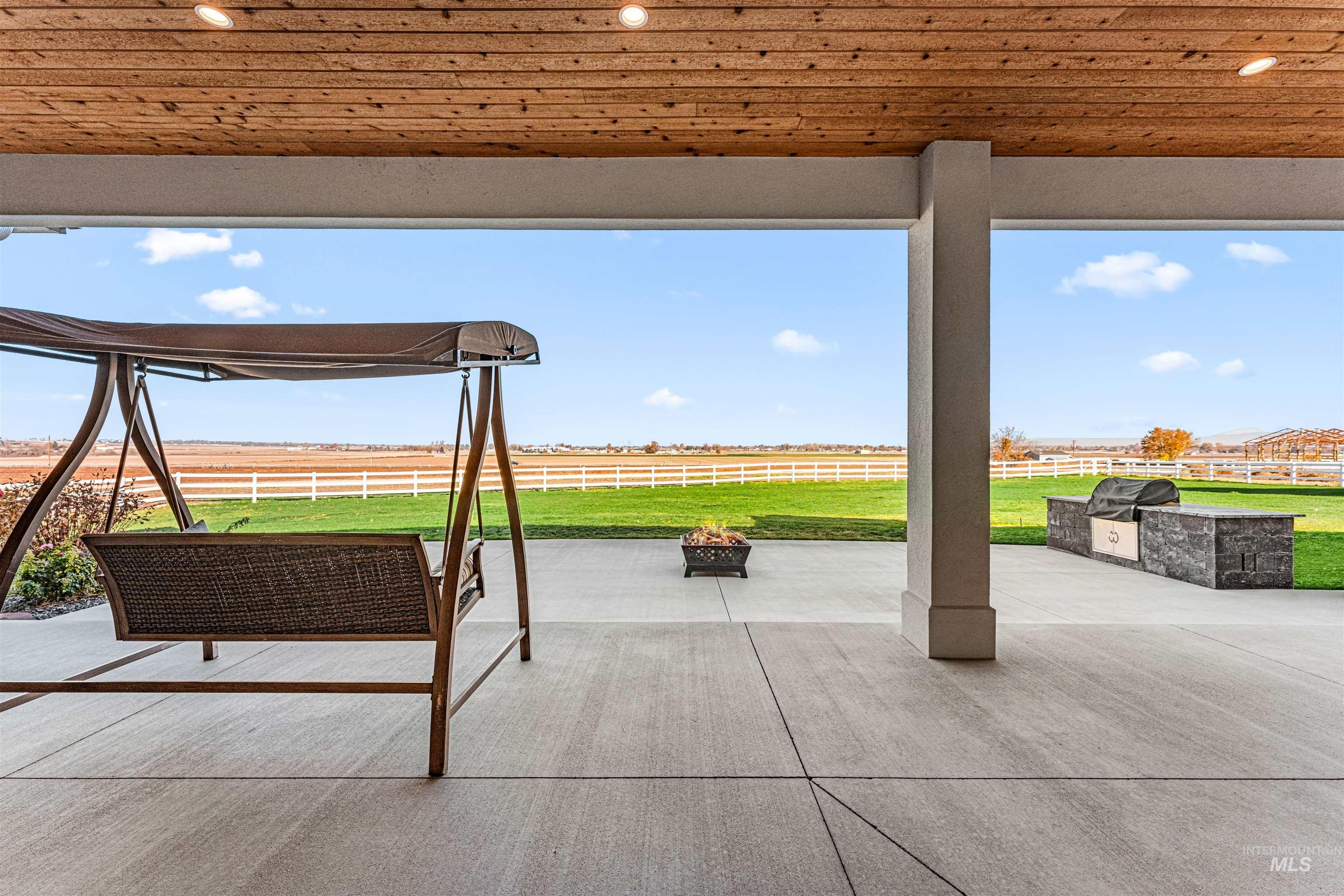 View of patio with an outdoor fire pit, grilling area, and a rural view