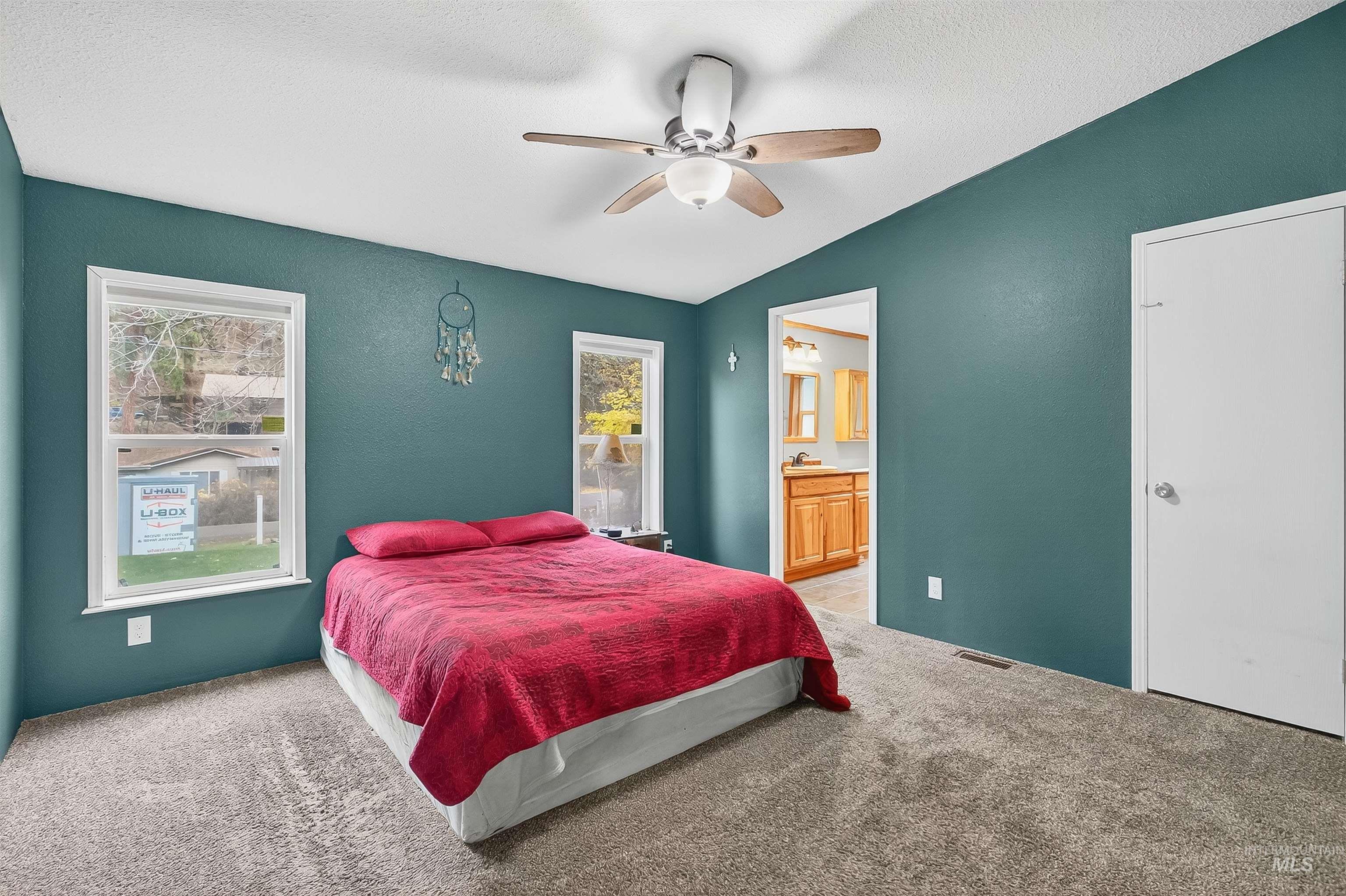 Bedroom with light carpet, ensuite bath, a textured ceiling, a ceiling fan, and lofted ceiling