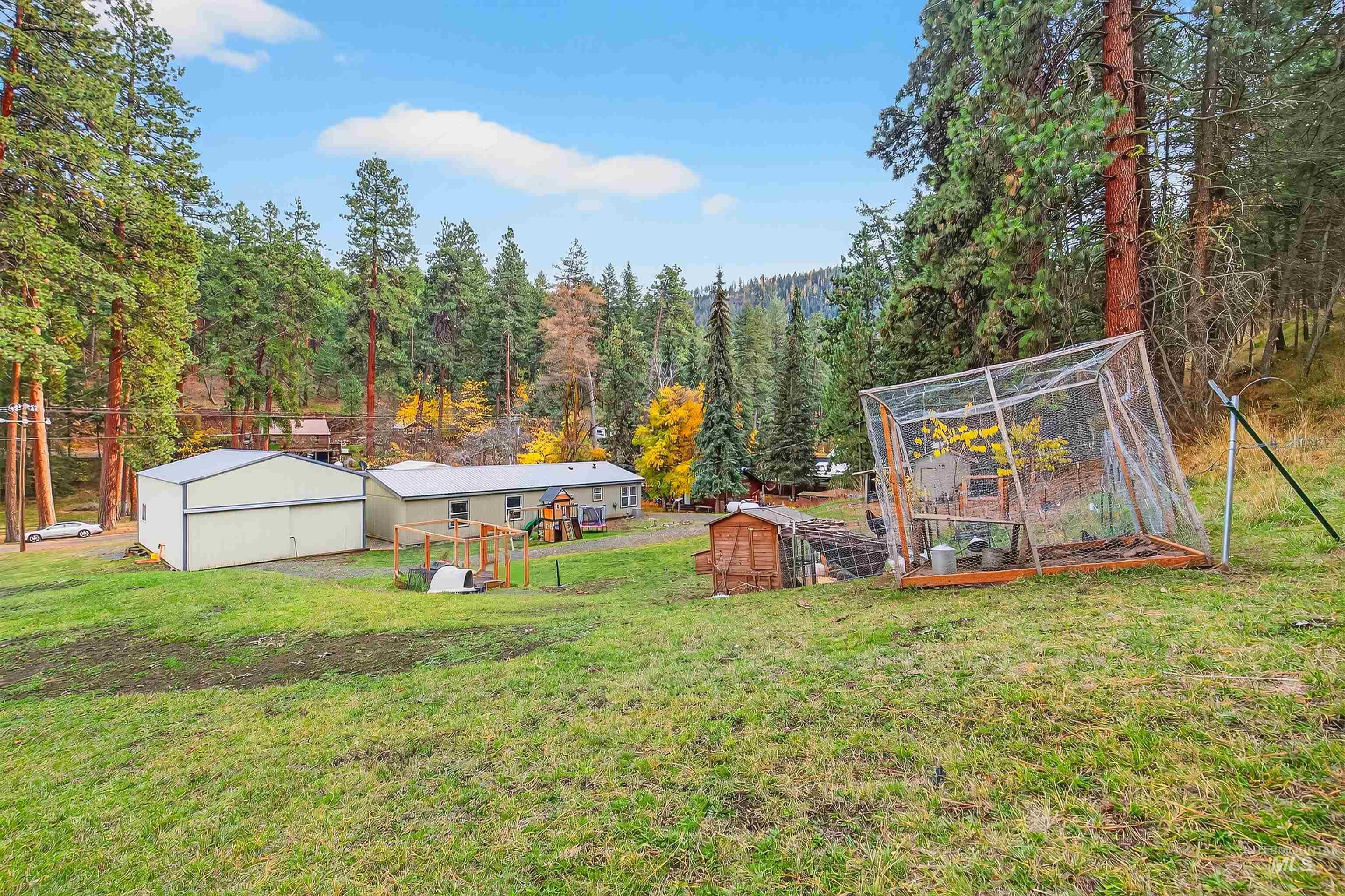 View of grassy yard featuring an outbuilding, a garden, and a wooded view