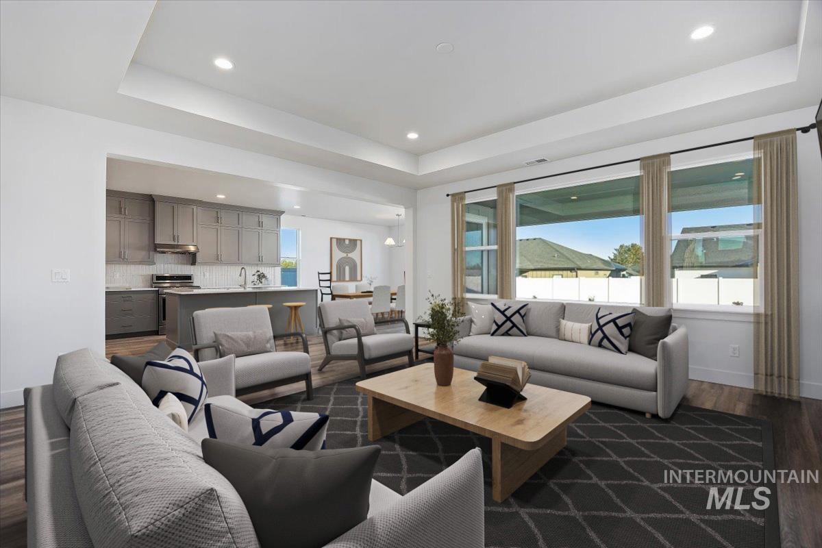 Living room featuring a tray ceiling, dark wood-style flooring, and recessed lighting