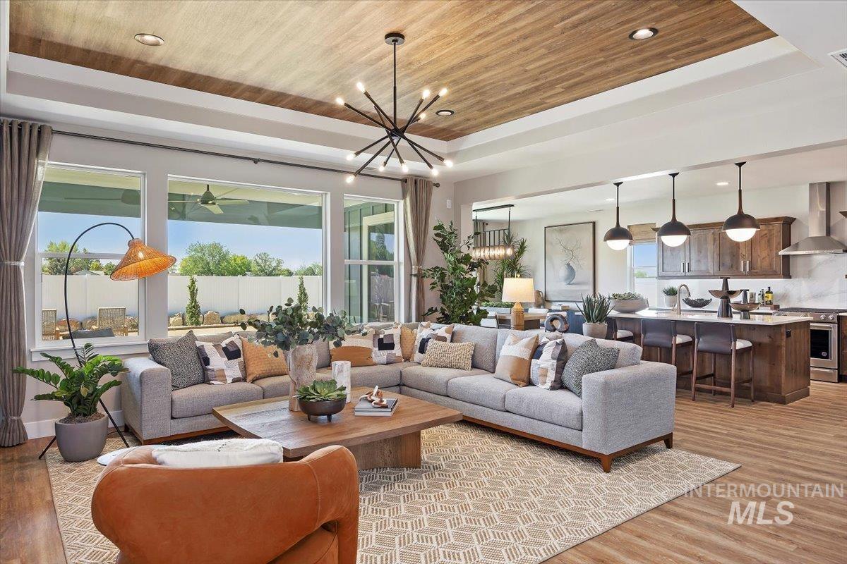 Living area with light wood-style flooring, wood ceiling, a raised ceiling, recessed lighting, and a chandelier