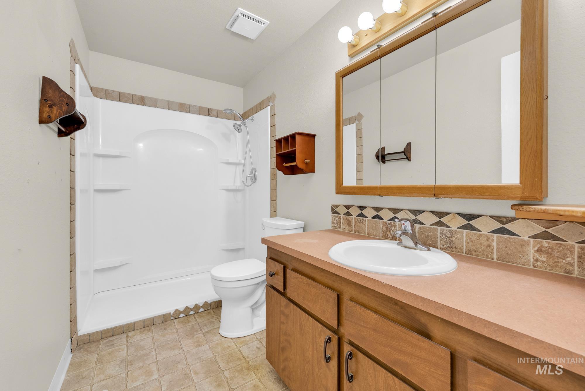 Full bathroom with a shower, vanity, and decorative backsplash