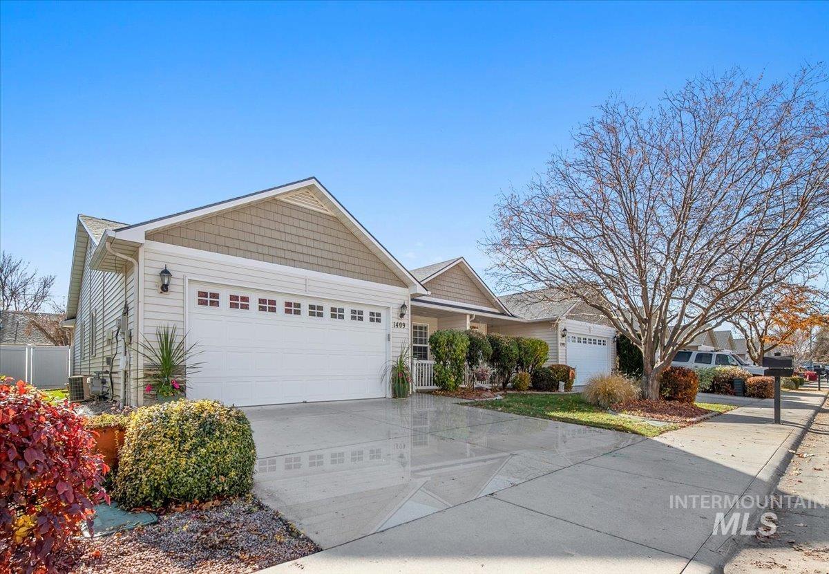 View of front of property with an attached garage, concrete driveway, and covered porch