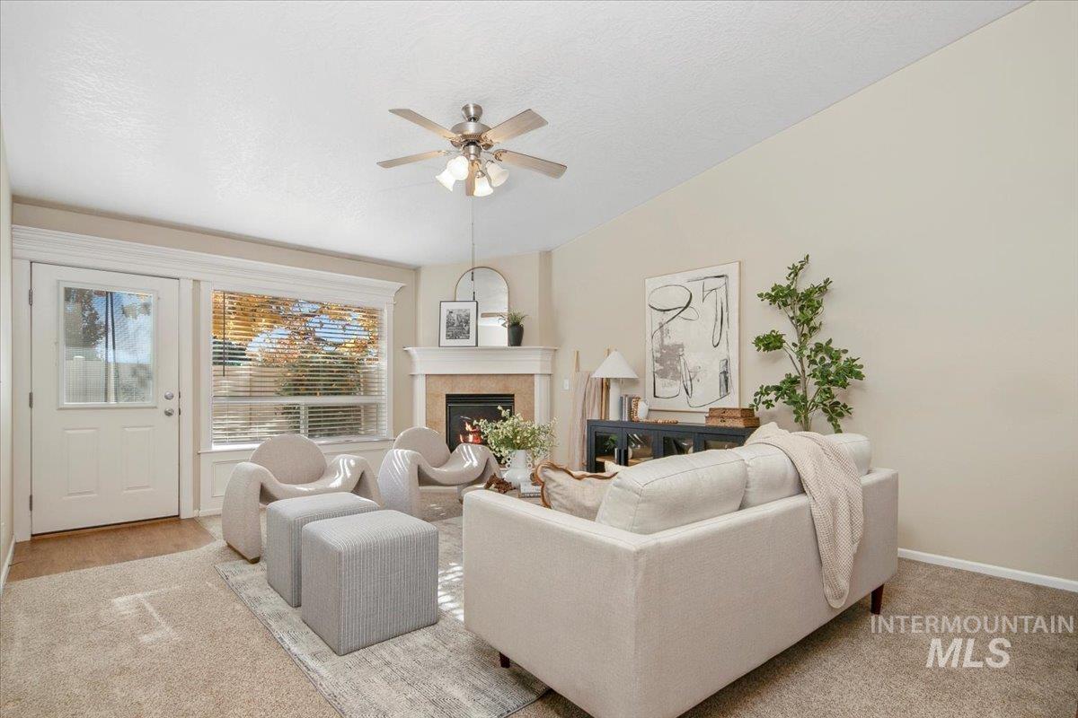 Living area with a warm lit fireplace, ceiling fan, and a textured ceiling
