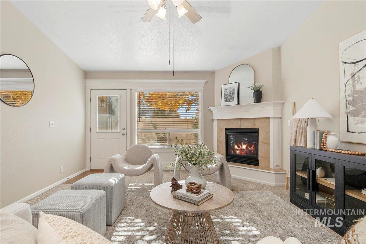 Living area with carpet, a textured ceiling, a fireplace, and ceiling fan