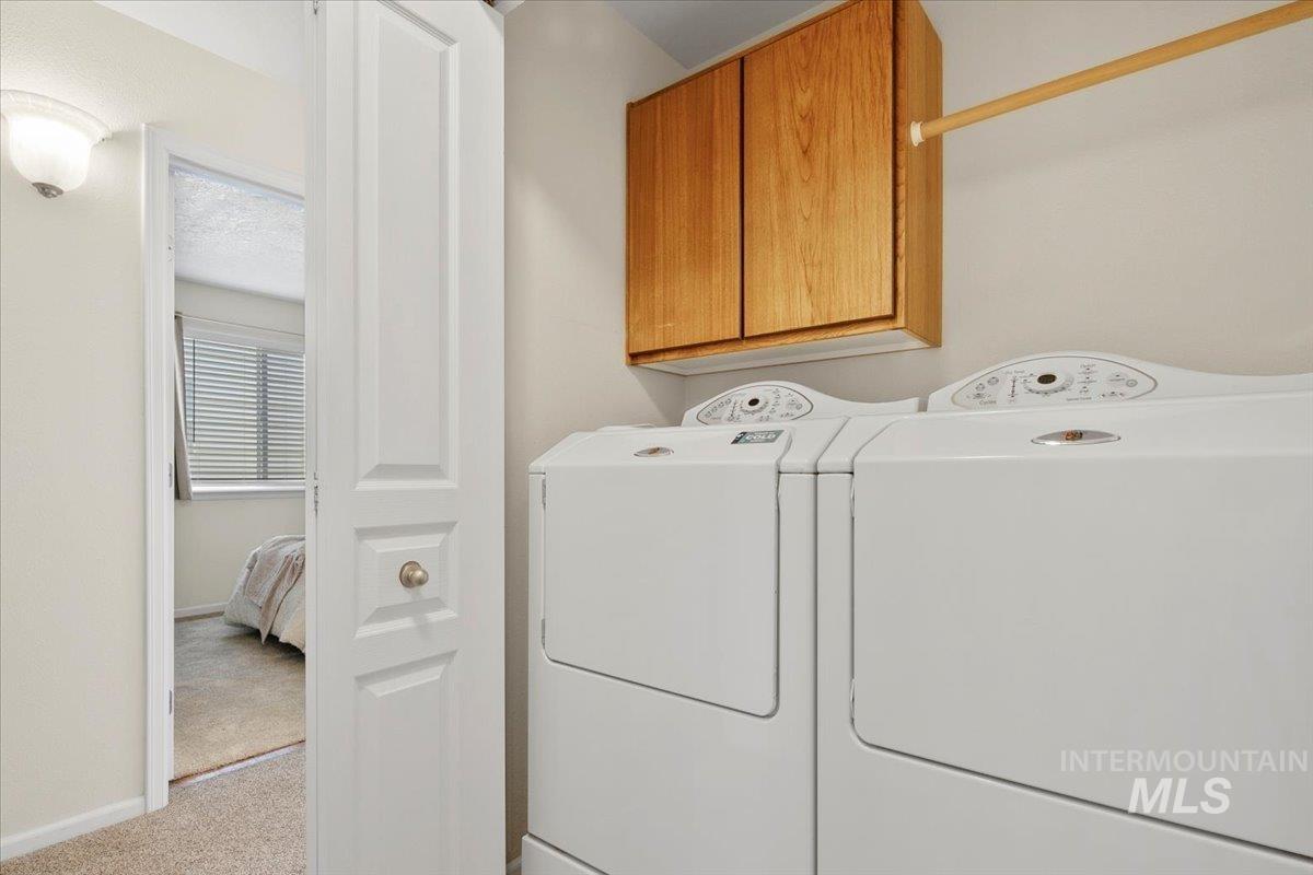 Laundry area with light carpet, separate washer and dryer, and cabinet space