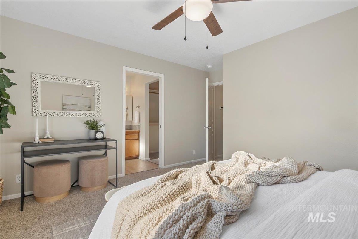 Carpeted bedroom with connected bathroom and ceiling fan