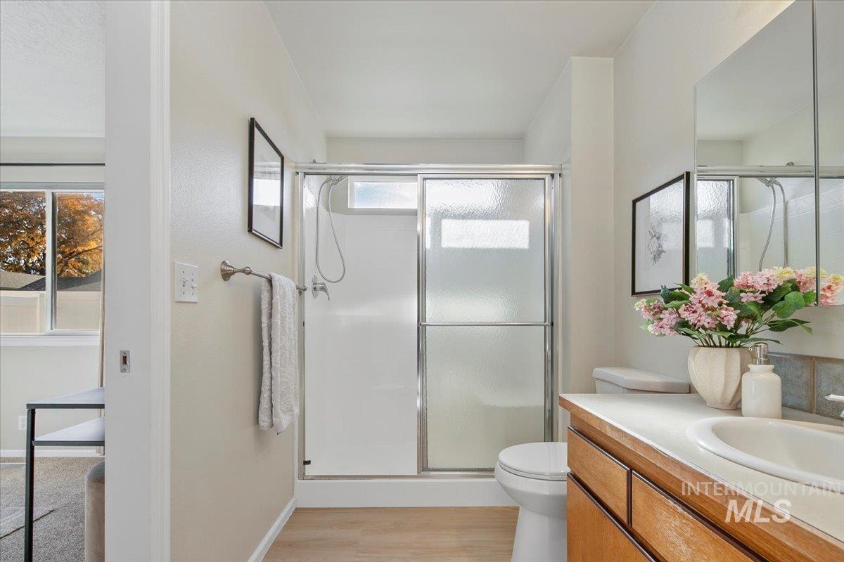 Full bath featuring vanity, a stall shower, and light wood finished floors