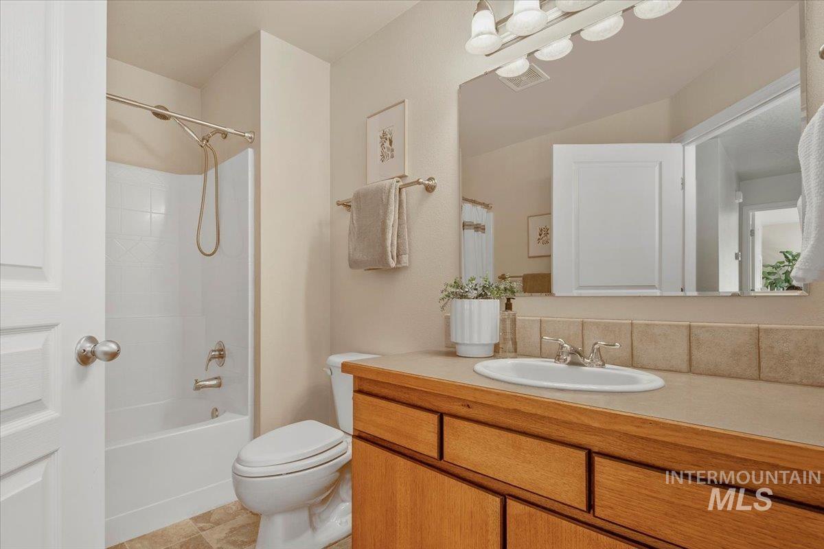 Full bathroom with shower / bathtub combination with curtain, vanity, and light tile patterned floors