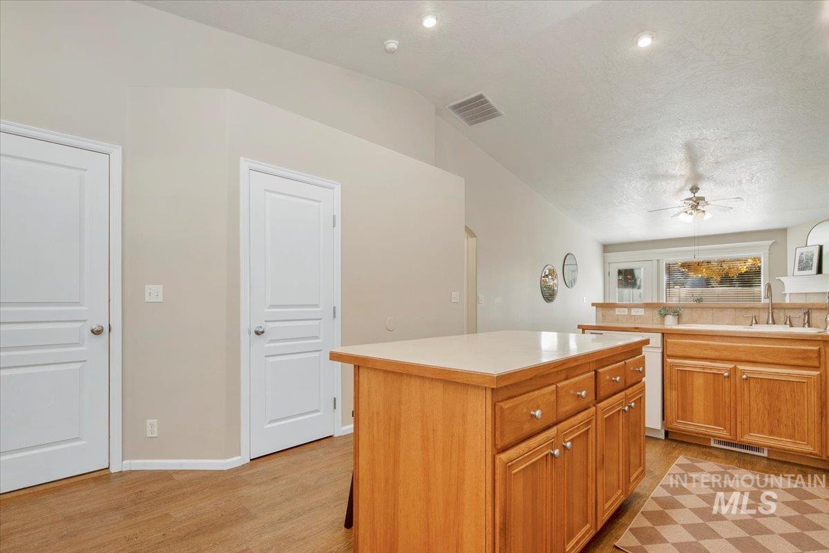 Kitchen with a kitchen island, light countertops, light wood-style floors, a ceiling fan, and brown cabinetry
