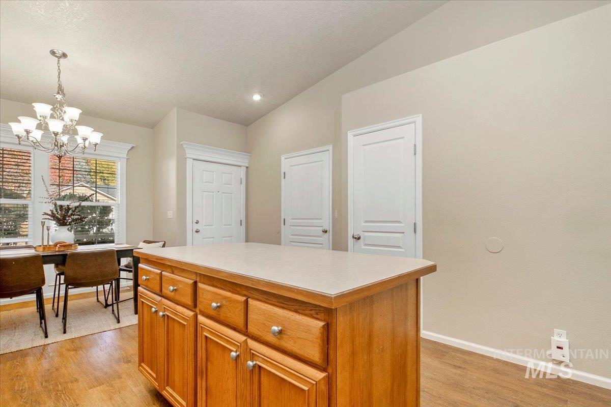 Kitchen with brown cabinetry, a center island, light countertops, light wood finished floors, and pendant lighting