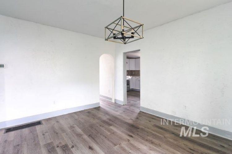 Unfurnished dining area with arched walkways and dark wood finished floors