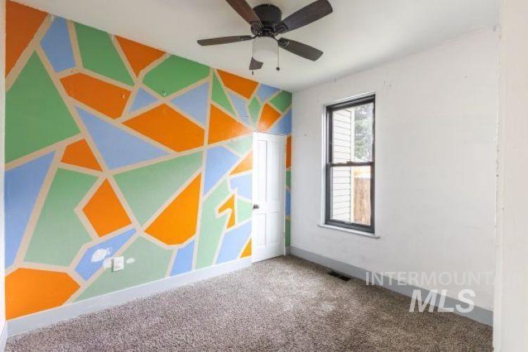 Carpeted spare room with a ceiling fan and baseboards